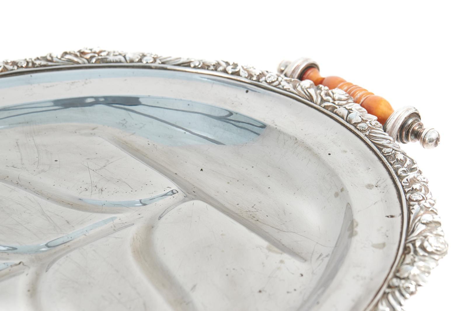 Grande vassoio per la carne/scaldavivande antico di qualità placcato in argento con bordo ornato di qualità e maniglie originali in legno per il trasporto, sollevato su piedini ornamentali sagomati.
Buone condizioni originali d'epoca.