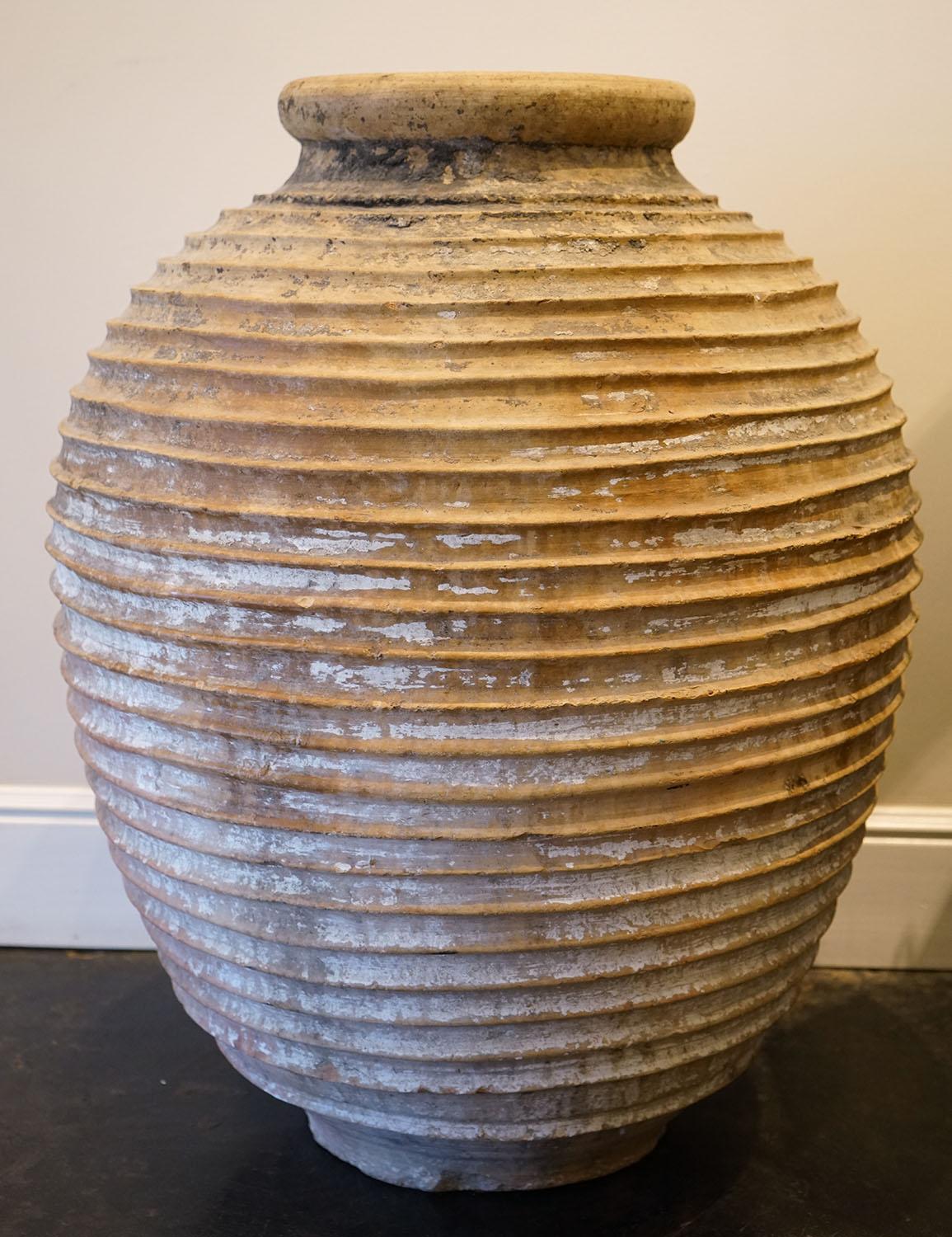 An early 19th century Mediterranean large size terracotta ribbed olive jar. This olive terracotta jar was born in the Mediterranean in the 1800s, where it was used to store olive oil. It features a typically Greek style with its ribbed body,