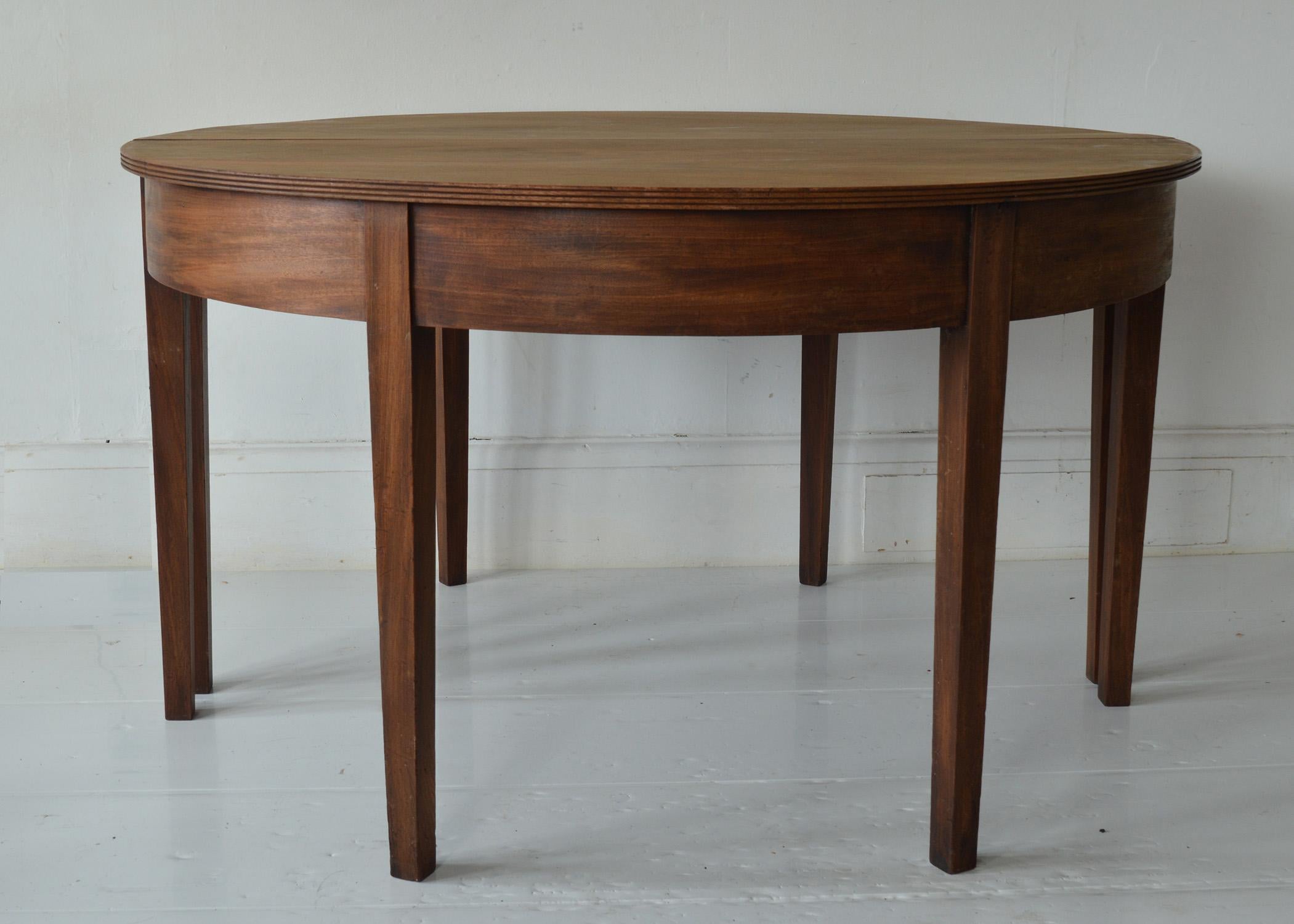 Fabulous large round table. Made from Cuban mahogany.

As round it would sit six. There is an extra leaf so would seat eight comfortably. You can also use it as a pair of demi-lunes.

Great simple lines. I particularly like the reeded edge on the