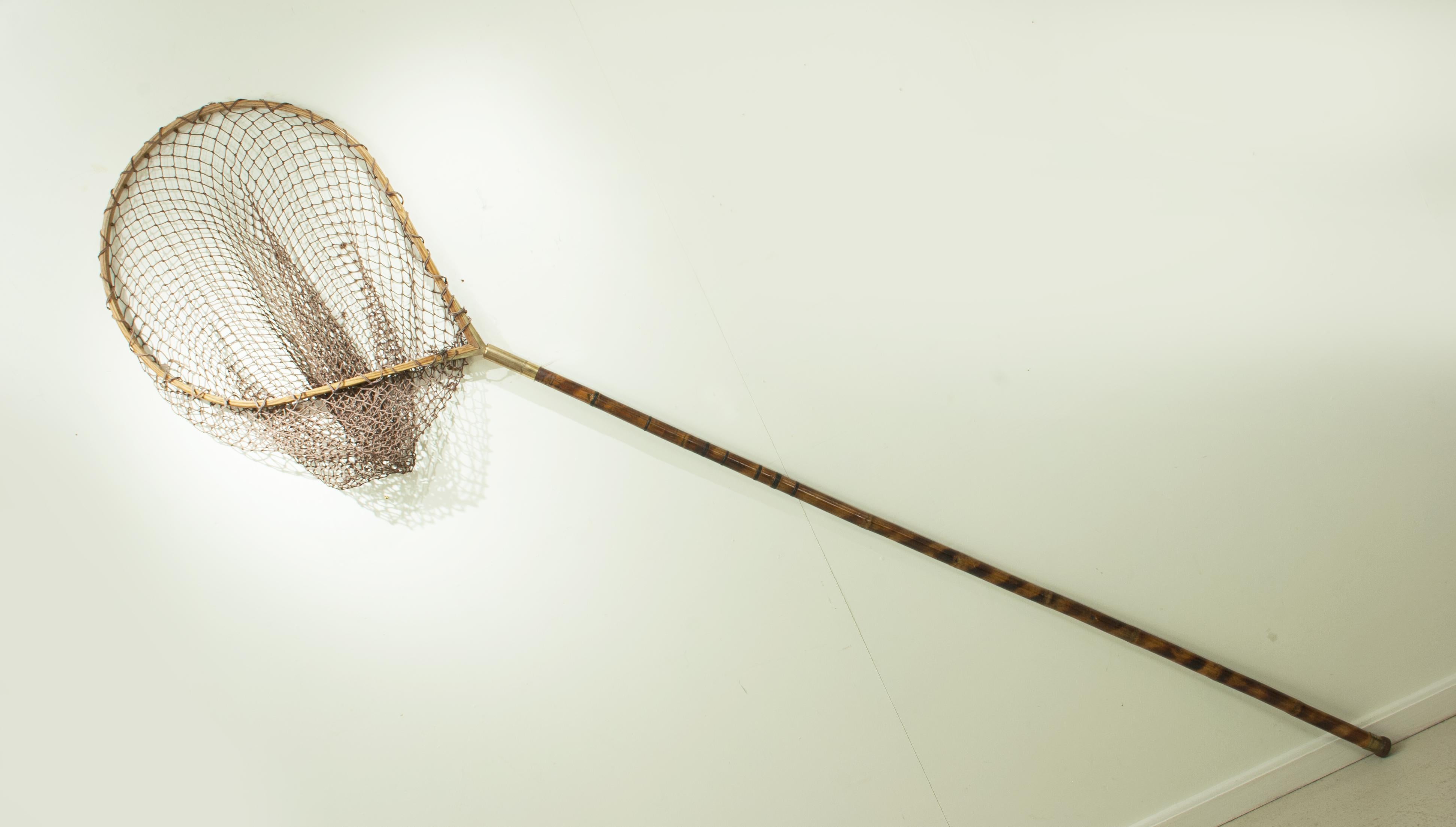 Vintage 8 ft salmon landing net. A good large salmon fishing landing net with a bent ash hoop head. The head of the net is with a good strung net and unscrews from the long bamboo shaft. A very nice net ideal for display purposes.

Collections: