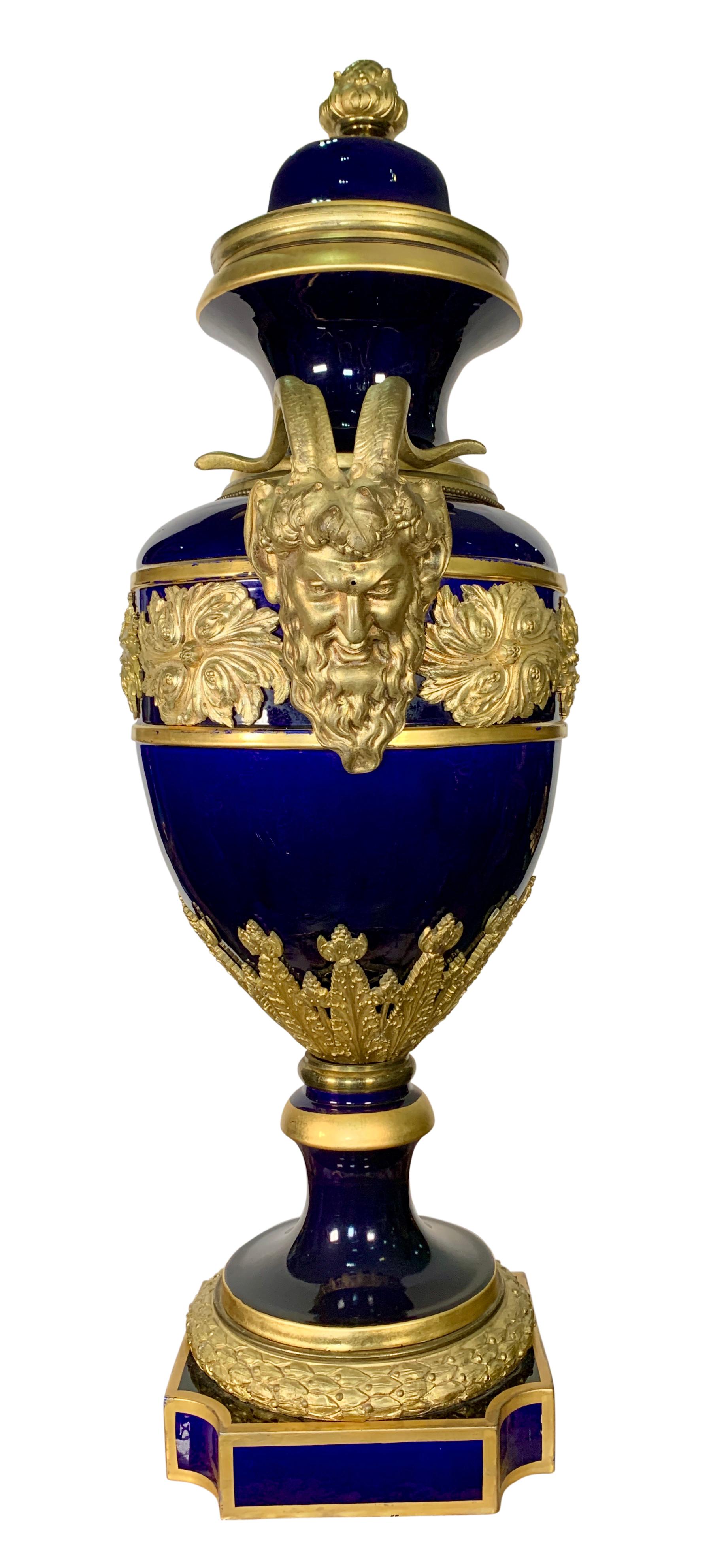 Grand et inhabituel vase / urne couvert monté en bronze doré de Sèvres, de forme ovoïde effilée, sur fond bleu de cobalt, datant du 19e siècle. Un homme barbu avec des poignées en forme de cornes flanque chaque côté de l'urne, la base du socle