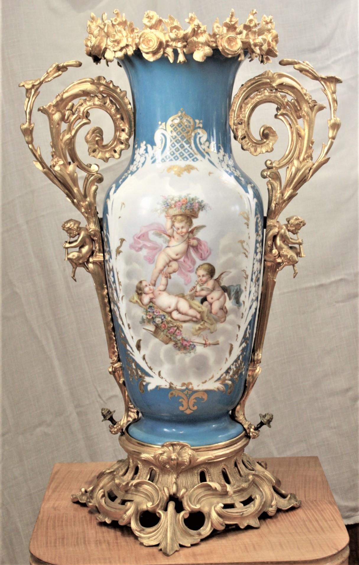 Ce grand vase ancien en porcelaine peint à la main n'est pas signé, mais on présume qu'il a été fabriqué en France vers 1880 dans le style de Sèvres. Le vase est réalisé sur un fond bleu turquoise avec des panneaux peints à la main bien exécutés de