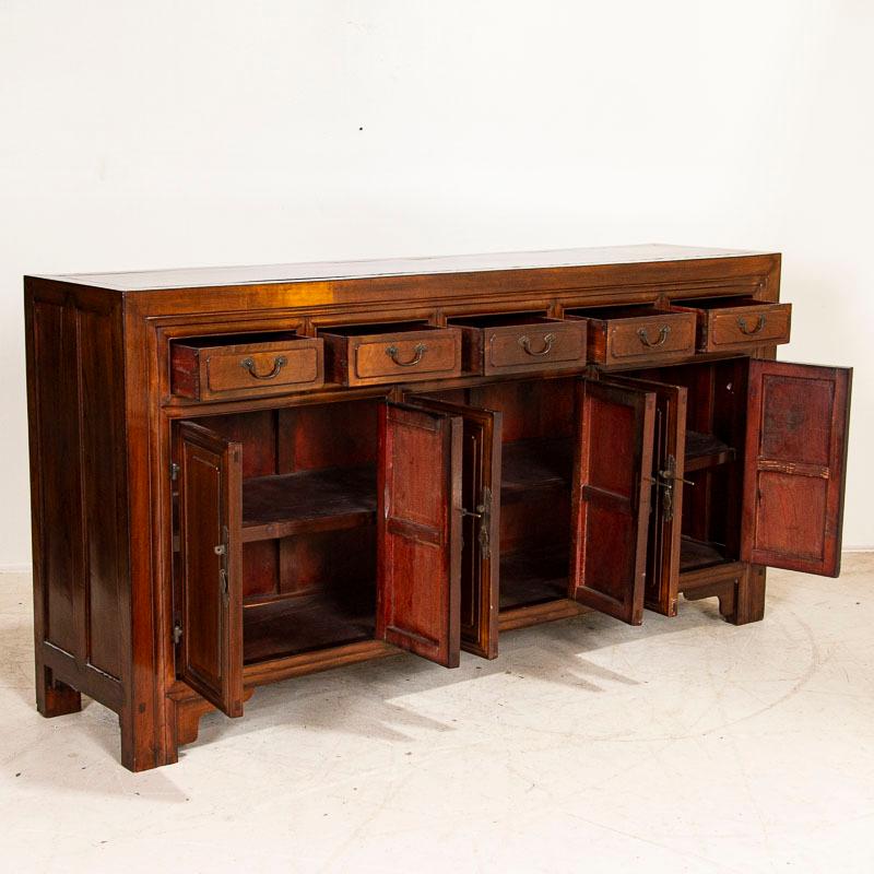 The lacquer finish on this striking antique Chinese sideboard is warm and inviting which accentuates the beauty of the elmwood. The balance of 5 drawers over 6 cabinet doors adds to the visual appeal as well. At 6.5' long, this sideboard will