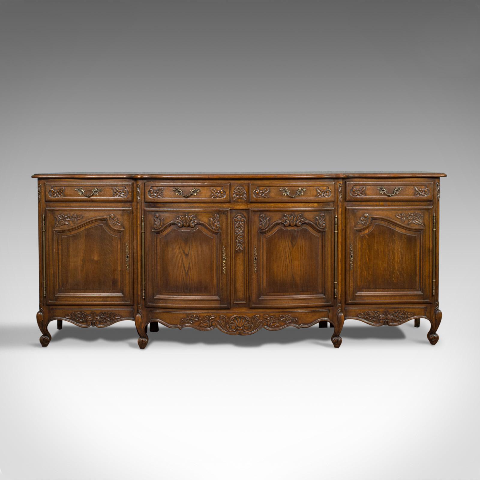 This is a large antique sideboard. A French, bow-fronted oak buffet cabinet of country house proportions at over 8 feet long, dating to the late 19th century, circa 1900.

Select oak displays warm caramel hues in a wax polished finish
Fine grain