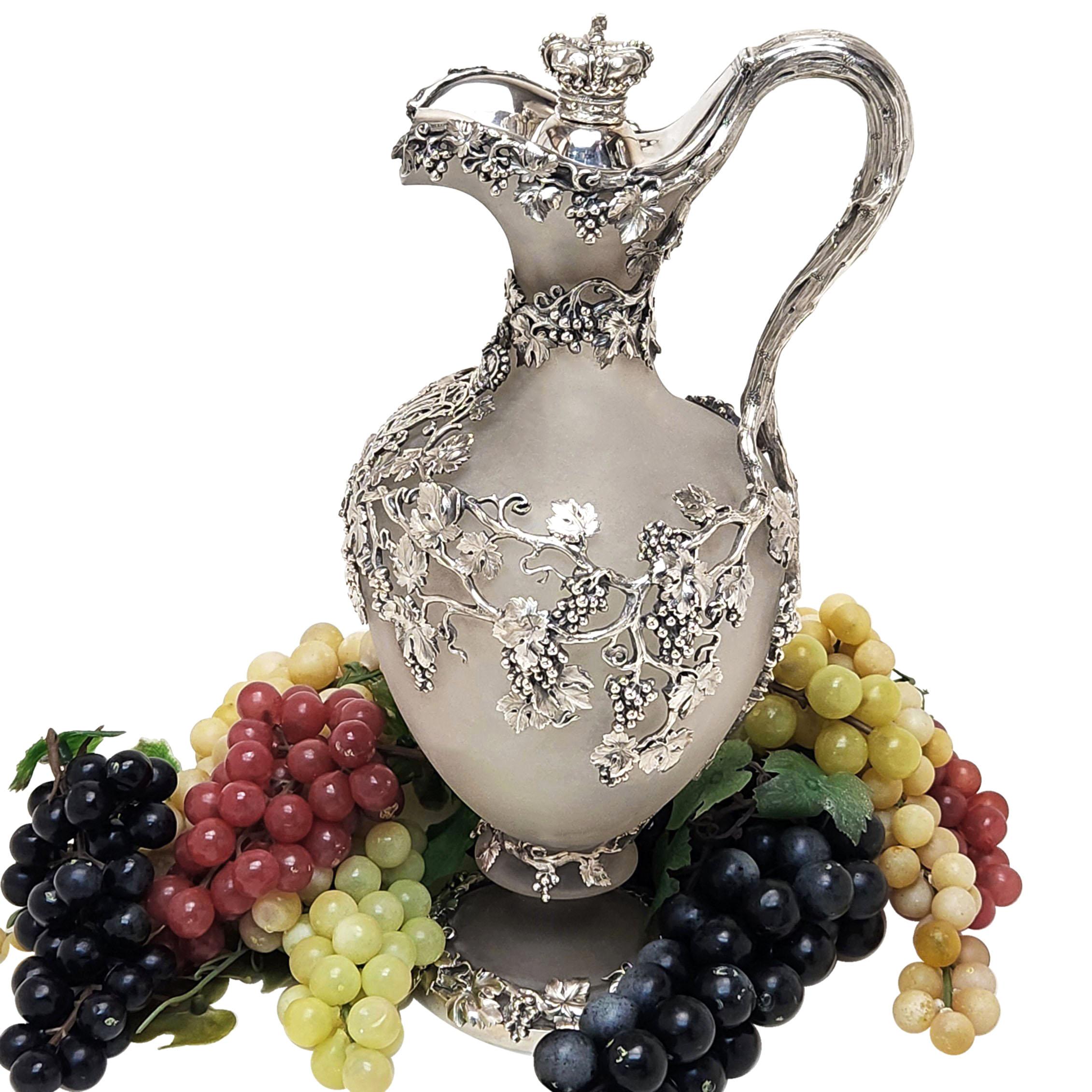 A magnificent Antique Victorian Silver Claret Jug with a frosted glass body and mounted with an ornate Sterling Silver grape vine design. The Silver grape vine pattern wraps wound the body of the Wine Jug and extends to the foot and hinged lid. The
