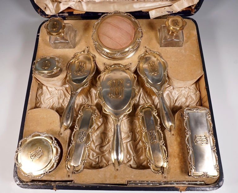 Black covered wooden case with original, cream-colored velvet and silk interior.
Contents: a small tray, two glass bottles, a powder box on feet, an oval glass box, four brushes, a hand mirror, a round silver box on feet, a rectangular box on feet