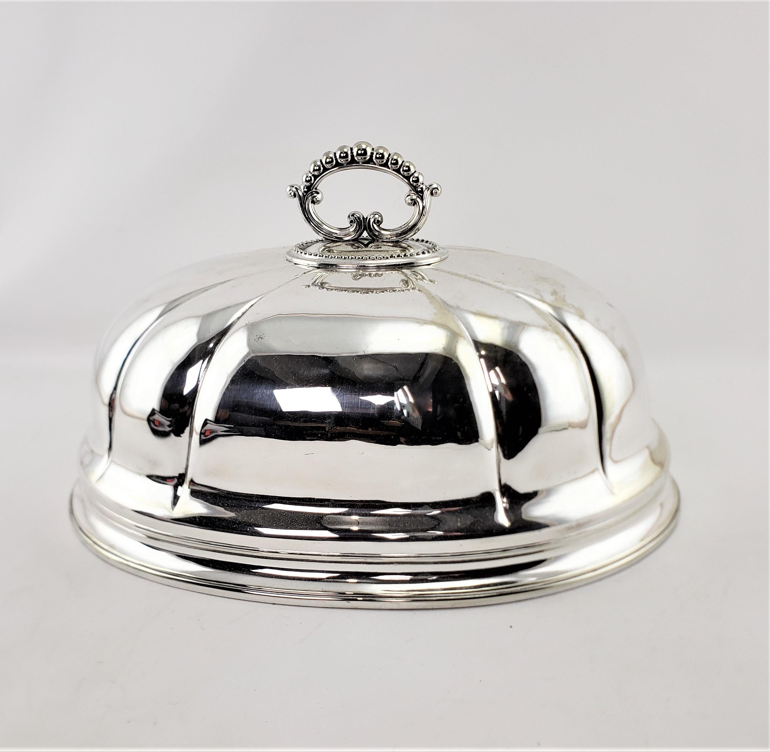 This large silver plated meat dome is unsigned, but presumed to have originated from England and dates to approximately 1900 and done in a period Edwardian style. The sides of the dome are done with a scalloped motif with a banding around the bottom