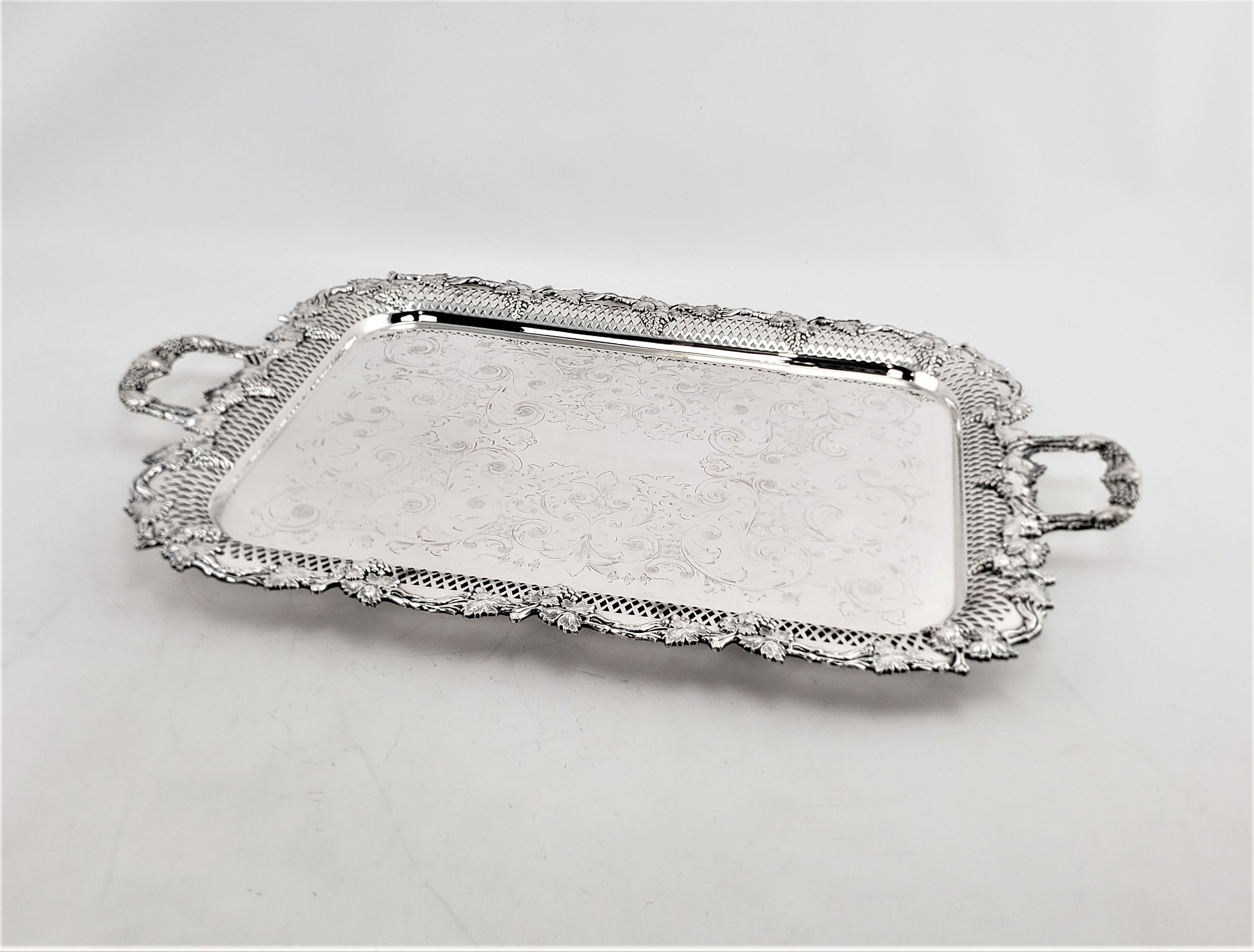 Esta gran bandeja para servir, antigua y ornamentada, fue fabricada por los conocidos plateros Wallace Silversmiths de Inglaterra aproximadamente en 1910, en el estilo eduardiano de la época. La bandeja está muy elaboradamente decorada alrededor de