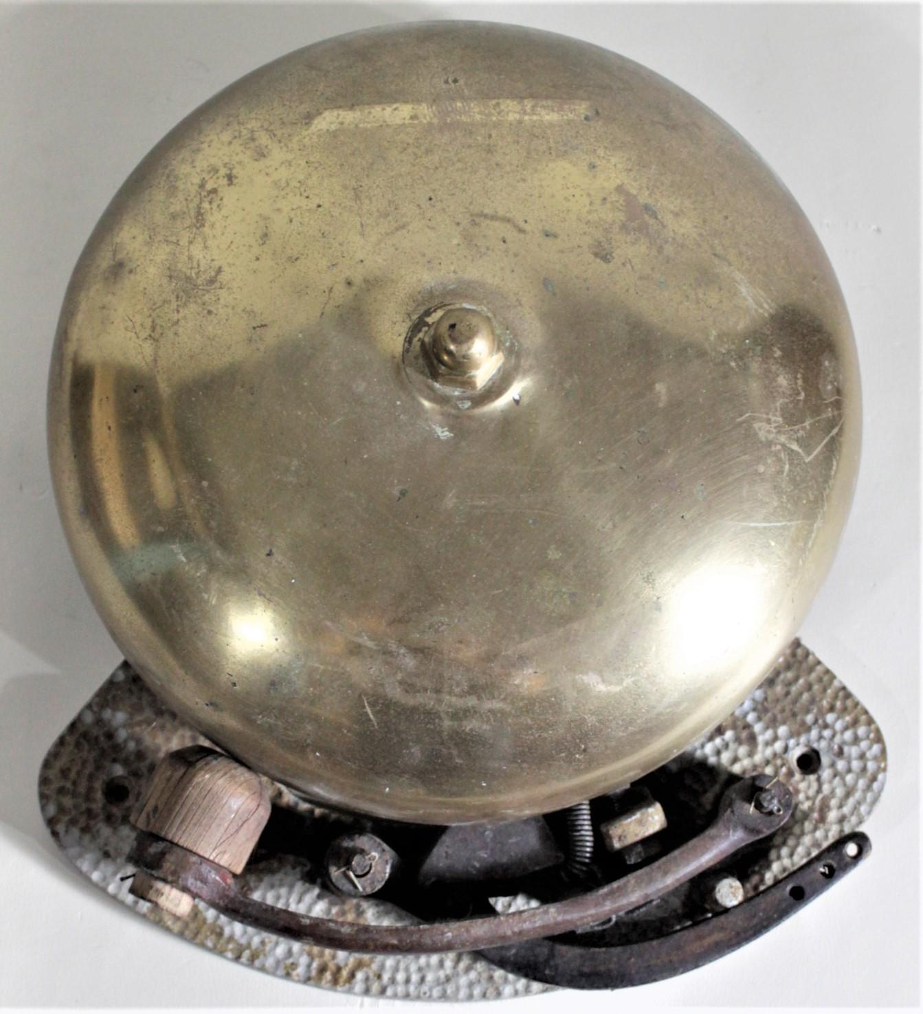 Cette cloche mécanique en laiton massif et en métal moulé ne porte pas de marque de fabricant, mais on pense qu'elle a été fabriquée aux États-Unis vers 1900. La cloche est conçue dans le style classique des 