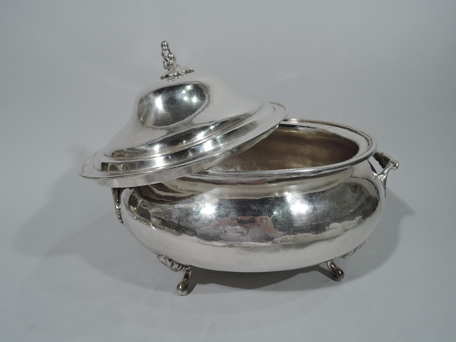 Large South American silver covered tureen, 19th century. Oval and bellied. End bracket handles leaf “wrapped” and mounted. Four leaf-mounted scroll supports. Rim interior cabled. Cover domed with ring-finial in form of drooping flower with
