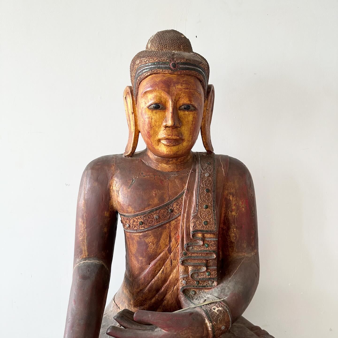 Larger than life, exquisite wooden Southeast Asian Buddha statue in Bhumisparsha mudra pose. The figure is solid wood painted red with gilded highlights. 

Bhumisparsha translates into 'touching the earth'.
It is more commonly known as the 'earth
