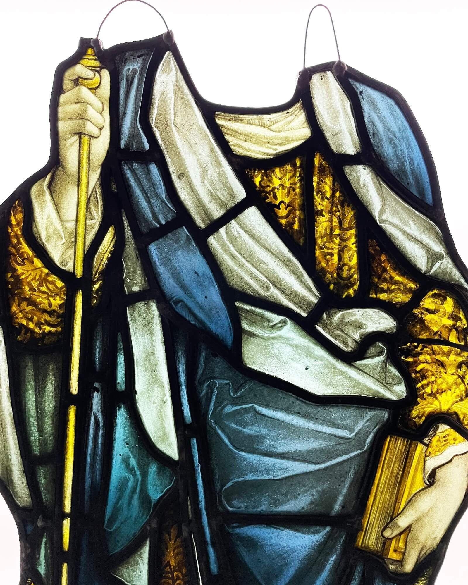 A large antique stained glass hanging panel of a nobleman’s torso dating to circa 1850. The vivid colour of this well-painted stained glass window has stood the test of time. At over 150 years old, the panel shows a nobleman carrying a book, robe,
