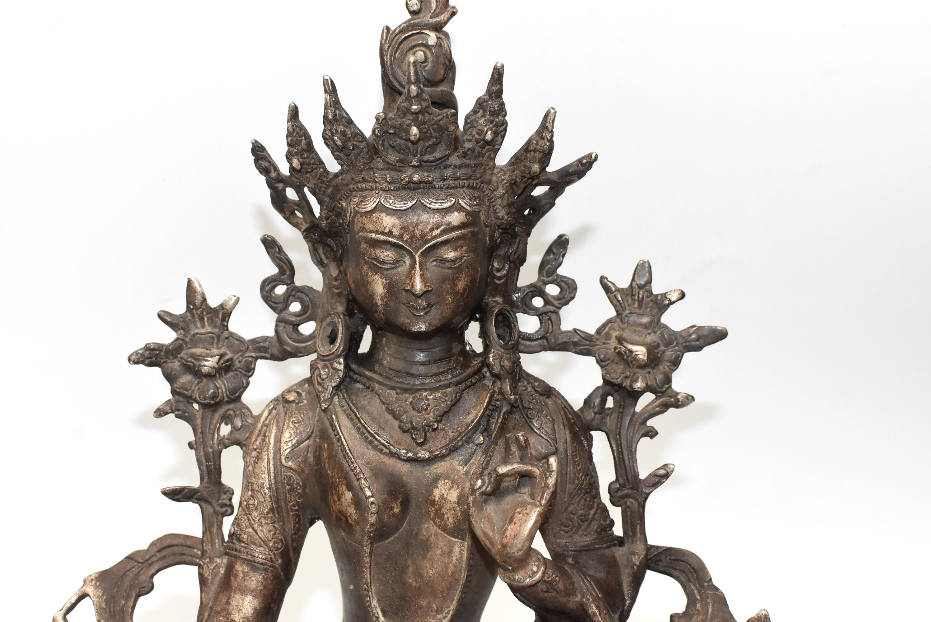 A beautiful, large antique Tibetan Tara statue. The white Tara is seated on a large lotus throne. She wears a highly decorated crown and a fluid robe embossed with flowers and scrolls, her body is draped with lariats of pearls. Fine facial features