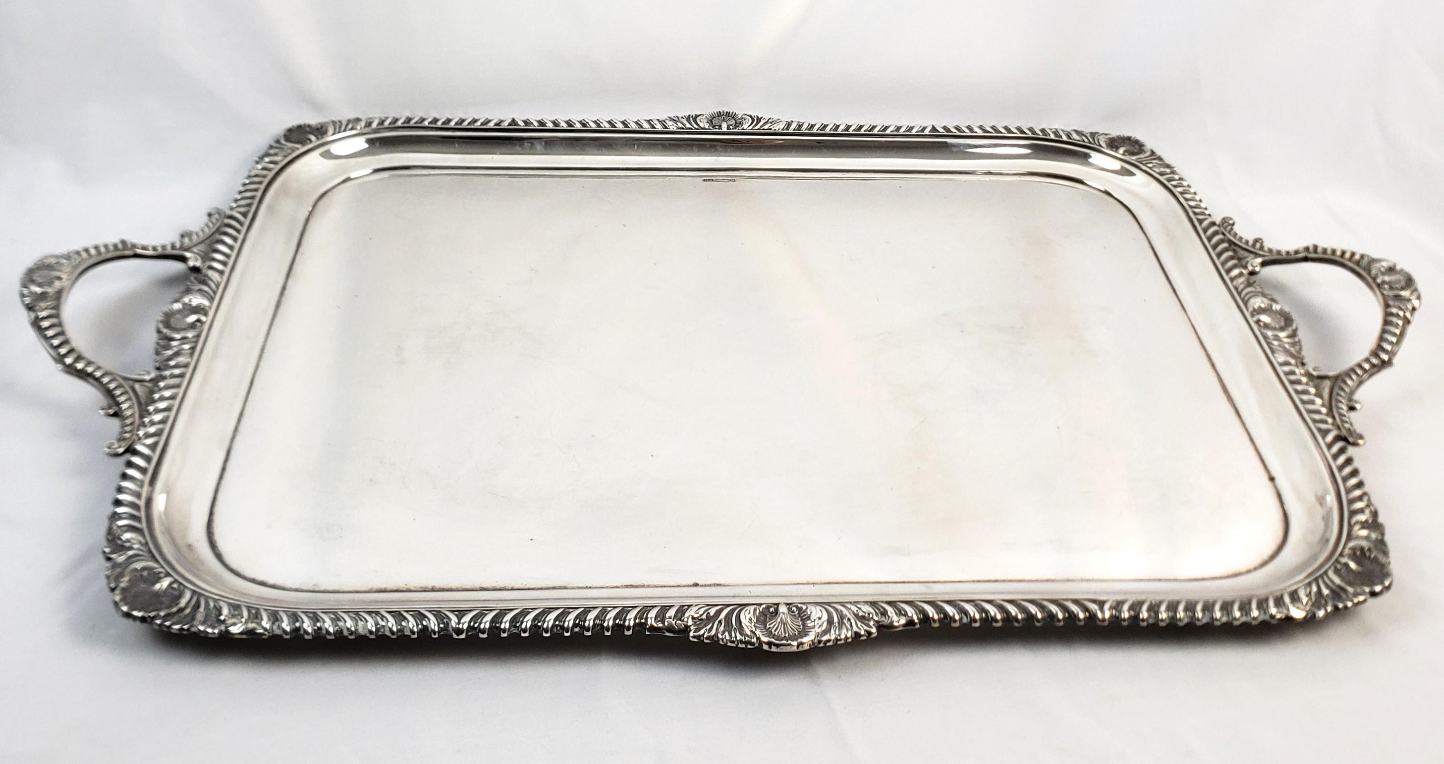 This very large and substantial antique serving tray was made by the Atkins Bros. silversmiths of England and dates to approximately 1900 and done in the period Edwardian style. The tray is composed of sterling silver and weighs in excess of four