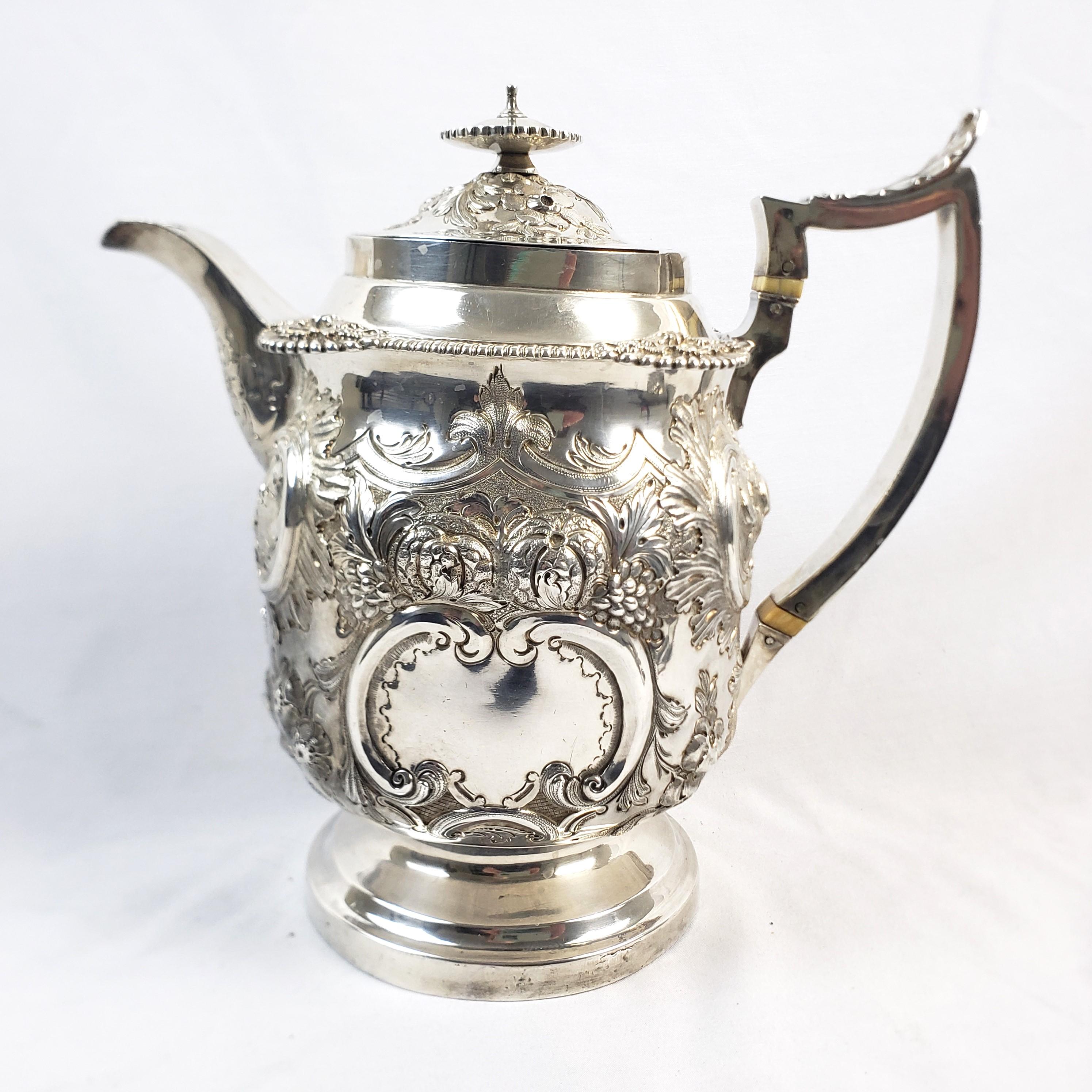 This antique teapot is unsigned, but originated from England and dates to approximately 1817 and done in the period Georgian style. The teapot is composed of sterling silver and is covered with very ornate raised or repousse floral and leaf