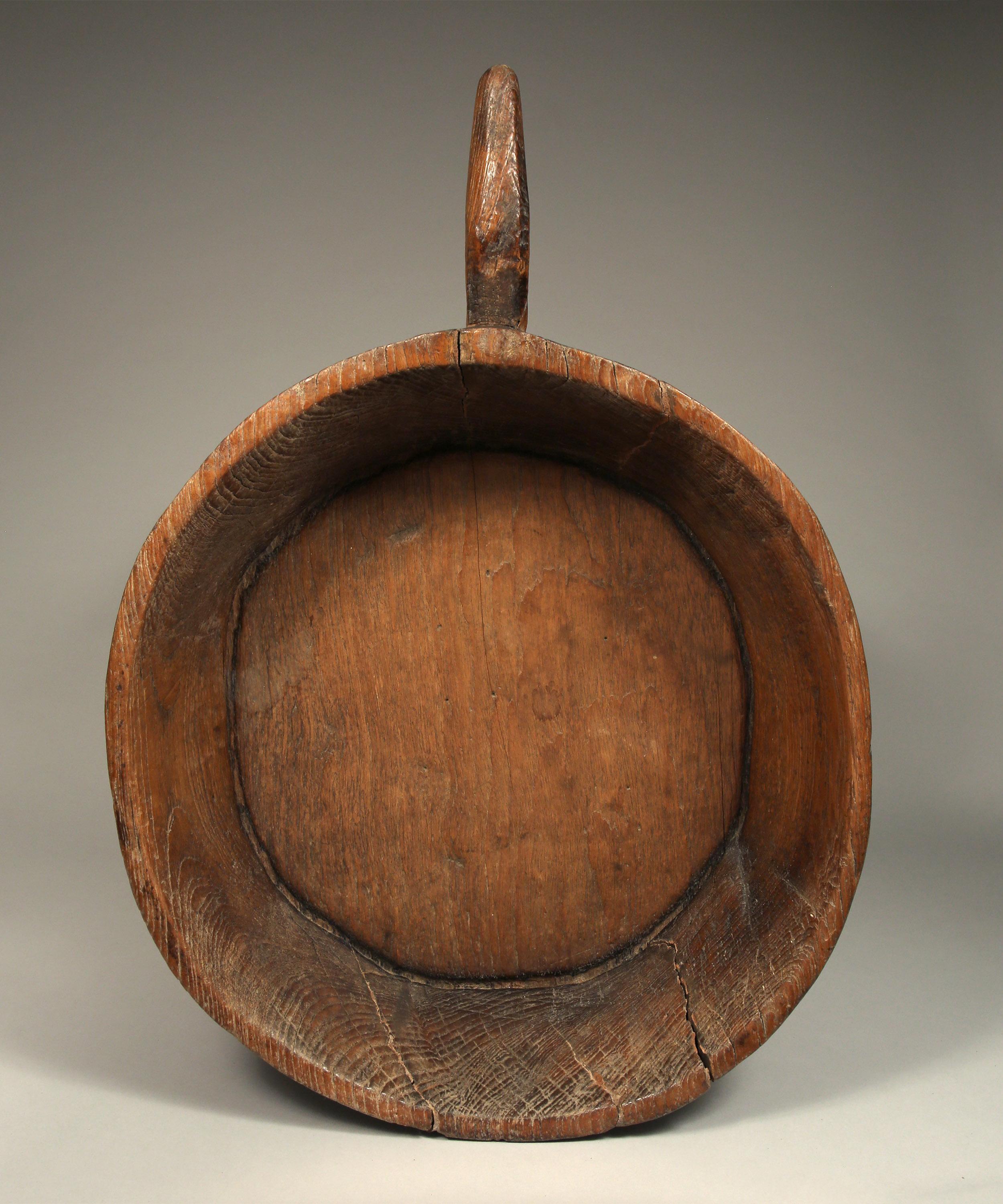 Large antique round teak bowl from Northern Thailand, early to mid-20th century.

Carved from one piece of dense teak wood including its handle.
Fine wood grain with rustic patina from village usage.
      