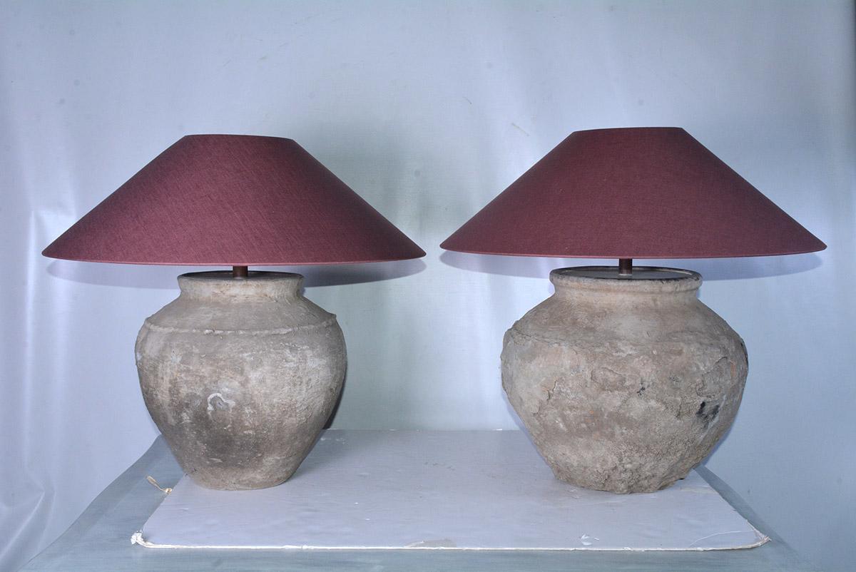 Two similar early large rustic organic Chinese unglazed terracotta storage jars that has been mounted as table lamps. The vases have beautiful aged patina from being buried perhaps for centuries. Handmade aubergine colored Belgium linen coolie shape