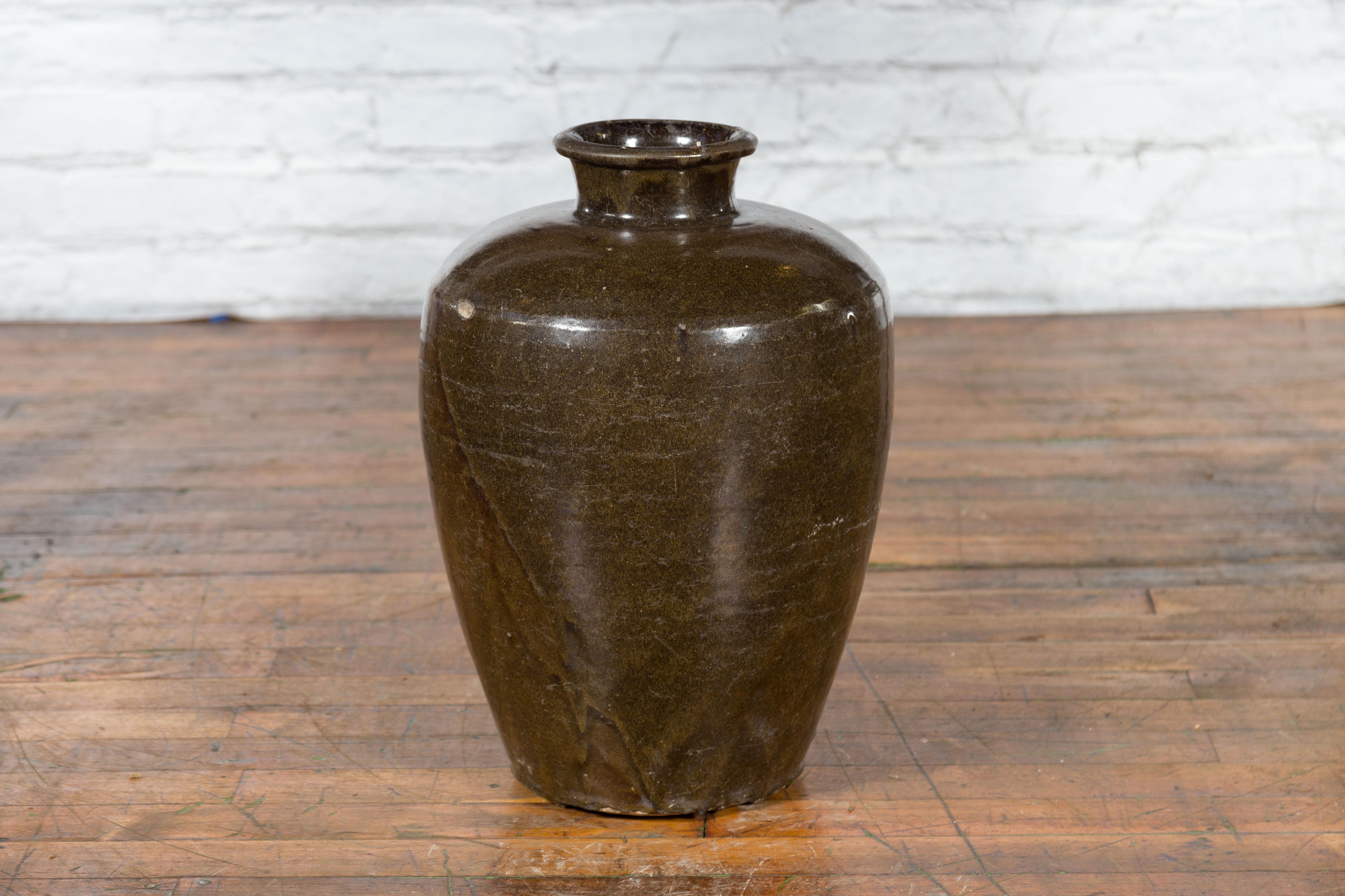 A large antique Thai storage jar from the early 20th century, with brown monochrome glazed finish and tapering lines. Created in Thailand during the early years of the 20th century, this storage jar features a circular mouth with large lip,