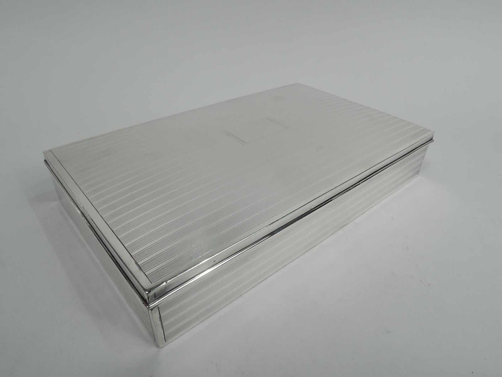 Large Art Deco sterling silver box. Made by Tiffany & Co. in New York, ca 1913. Rectangular with straight sides. Cover hinged with gently curved top. Engine-turned horizontal lines in plain frames on sides and cover. Cover top has plain central