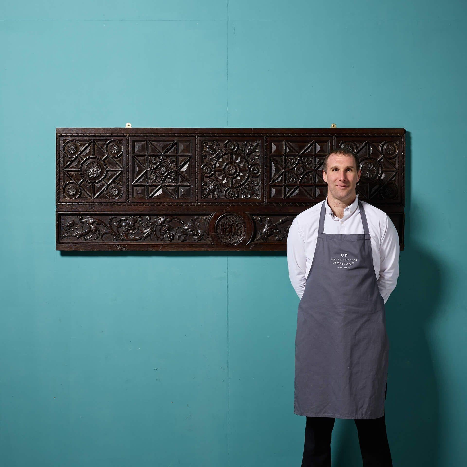A large scale antique Tudor / Jacobean revival oak wall panel carved with the date '1868' among various floral and geometric carved panels. This stunning period oak panel was reclaimed from Wingfield Castle, Suffolk. More than 150 years old, this