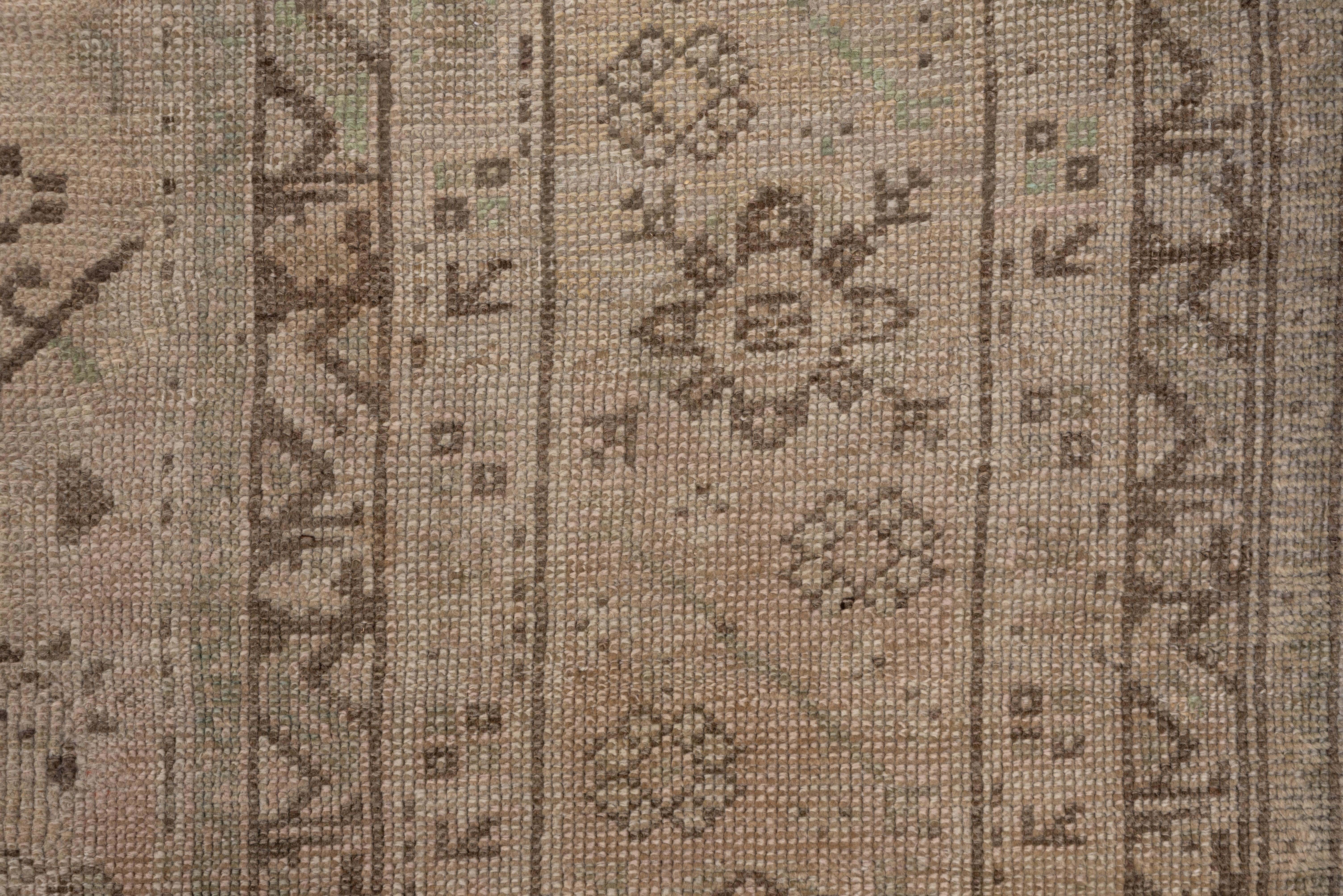This extra-large, west anatolian coarsely woven carpet shows a neutral field & green accents with a three column design of giant ragged palmettes and a central run of Yaprak (