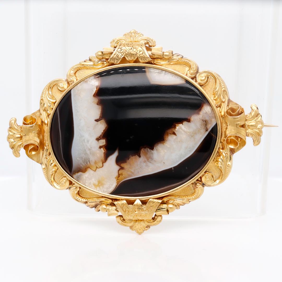 A fine antique Victorian brooch.

In 18k gold.

With a large bezel-set oval banded agate specimen in an ornate scrolling frame with etched decoration.

Simply a wonderful Victorian Period brooch!

Date:
1860s to 1870s

Overall Condition:
It is in