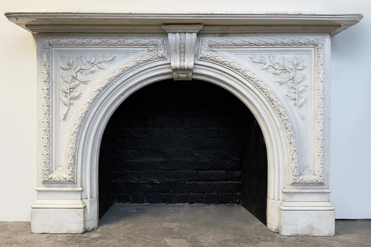 Very fine large antique mid Victorian white Statuary marble surround. The substantial shelf sits above a large arched fire surround. To the centre, a carved scrolled keystone supports the two arched sides with torus mouldings of laurel leaves each