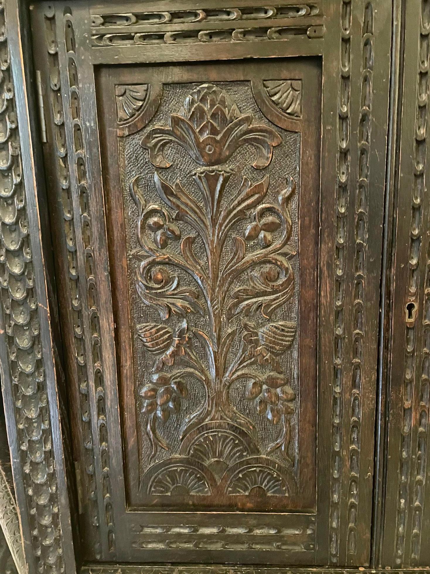 Large antique Victorian carved oak side cabinet having a shaped carved cornice above a single door flanked by two panels with superb carvings of fruit, flowers, leaves and scrolls, two open shelves with carved panels above the original mirrored