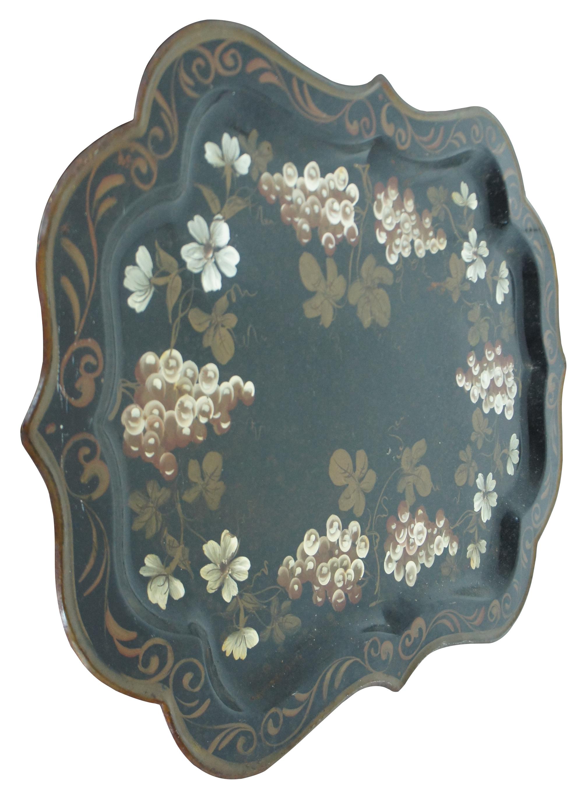 Large antique toleware, painted metal serving tray with scalloped edges bordered in gold, with a design of golden grapes and flowering vines.

