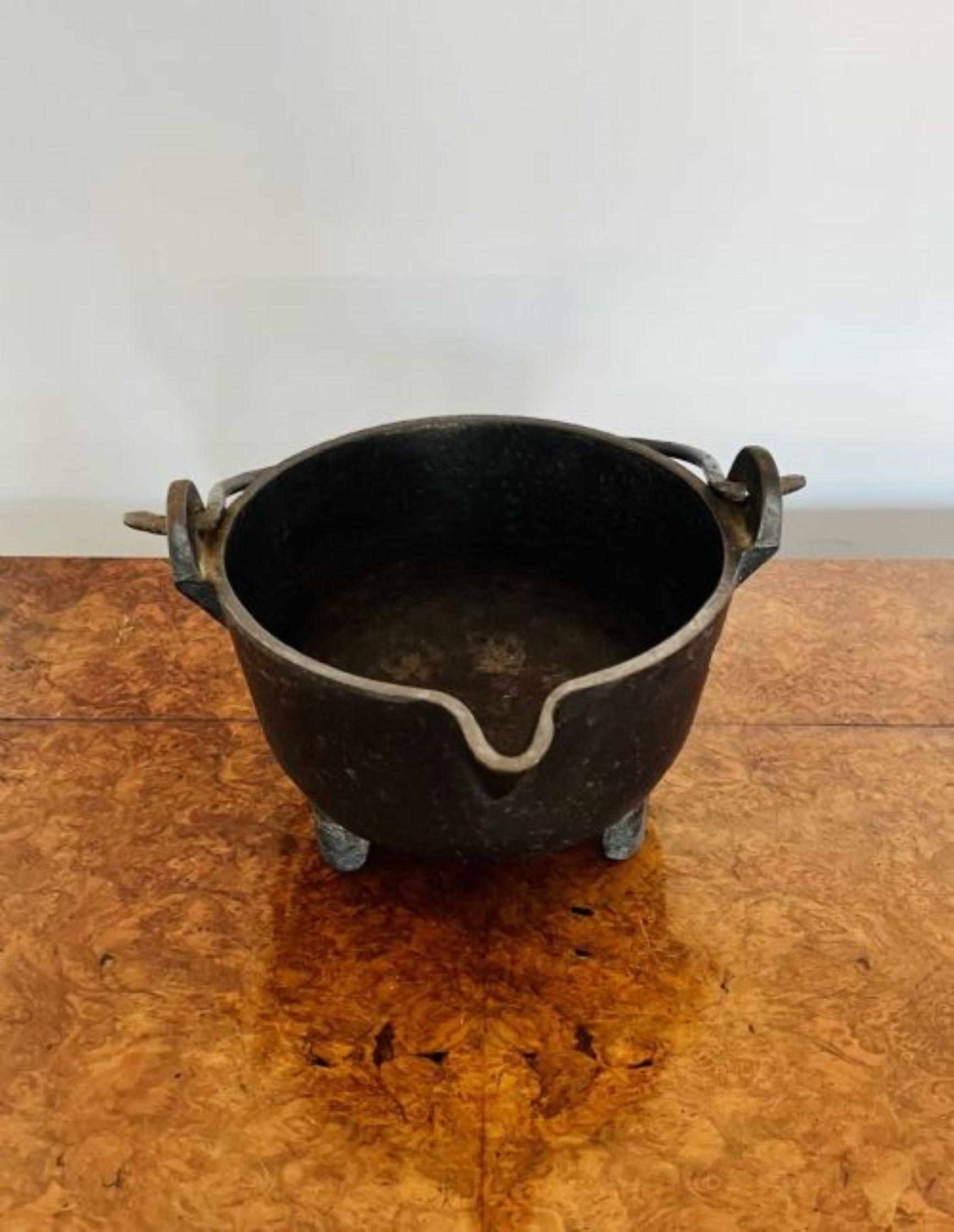 Large antique Victorian quality cast iron pot having a shaped swing handle above a large circular pot standing on square tapering feet.