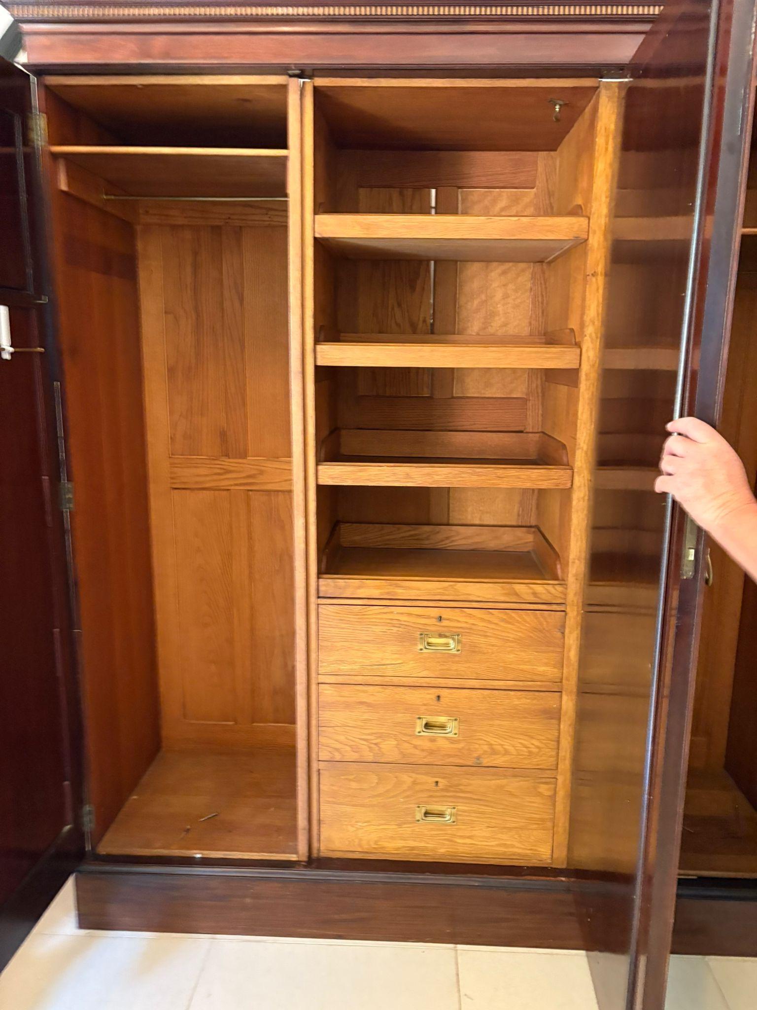 Large Antique Victorian quality inlaid figured mahogany 3 door wardrobe having a shaped inlaid cornice above a large bevelled edge mirror door opening to reveal a fitted interior consisting of 3 sliding trays and 3 drawers flanked by a pair of