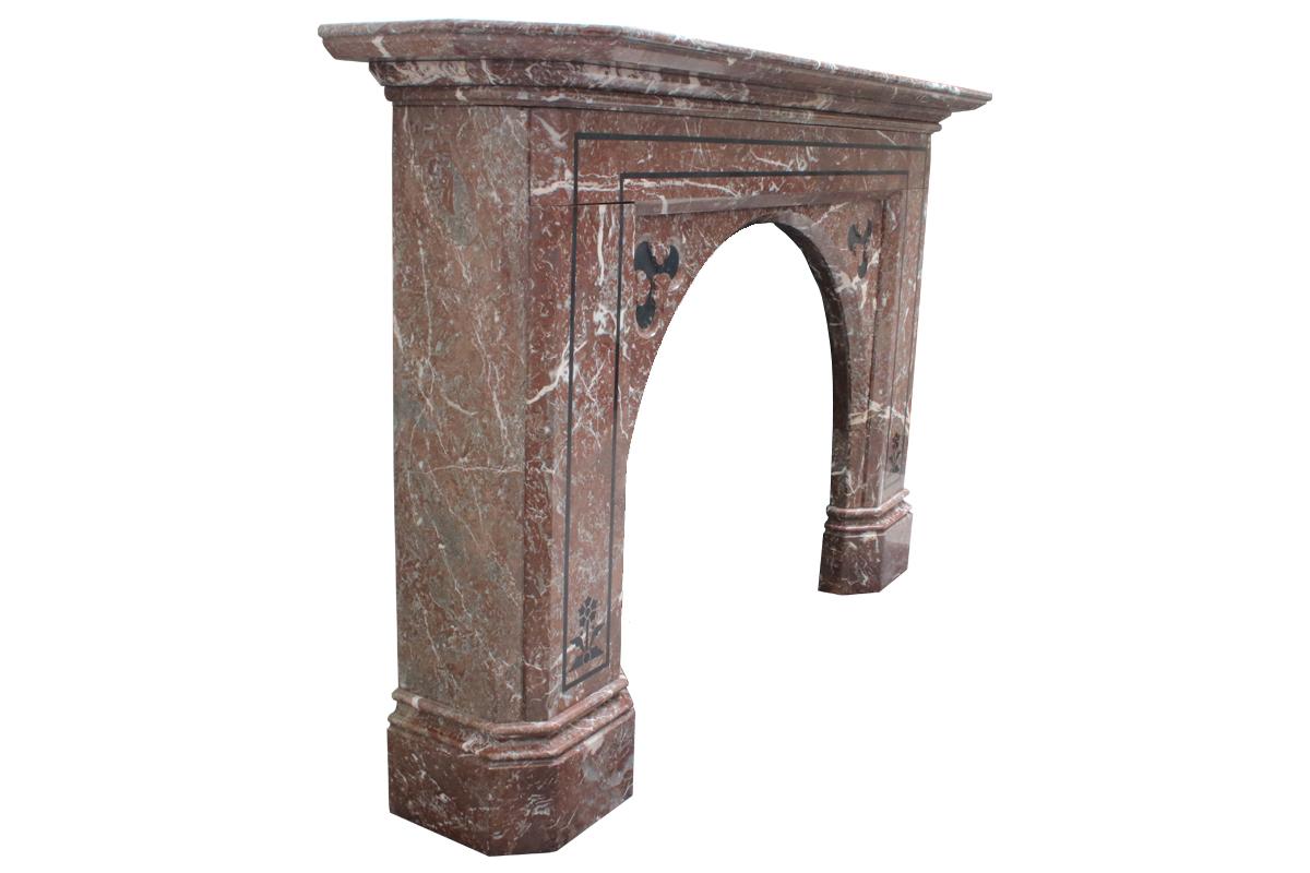 Magnificent antique mid-Victorian Rouge marble fireplace with an arched aperture, inlaid with black marble in the aesthetic manner, circa 1860.