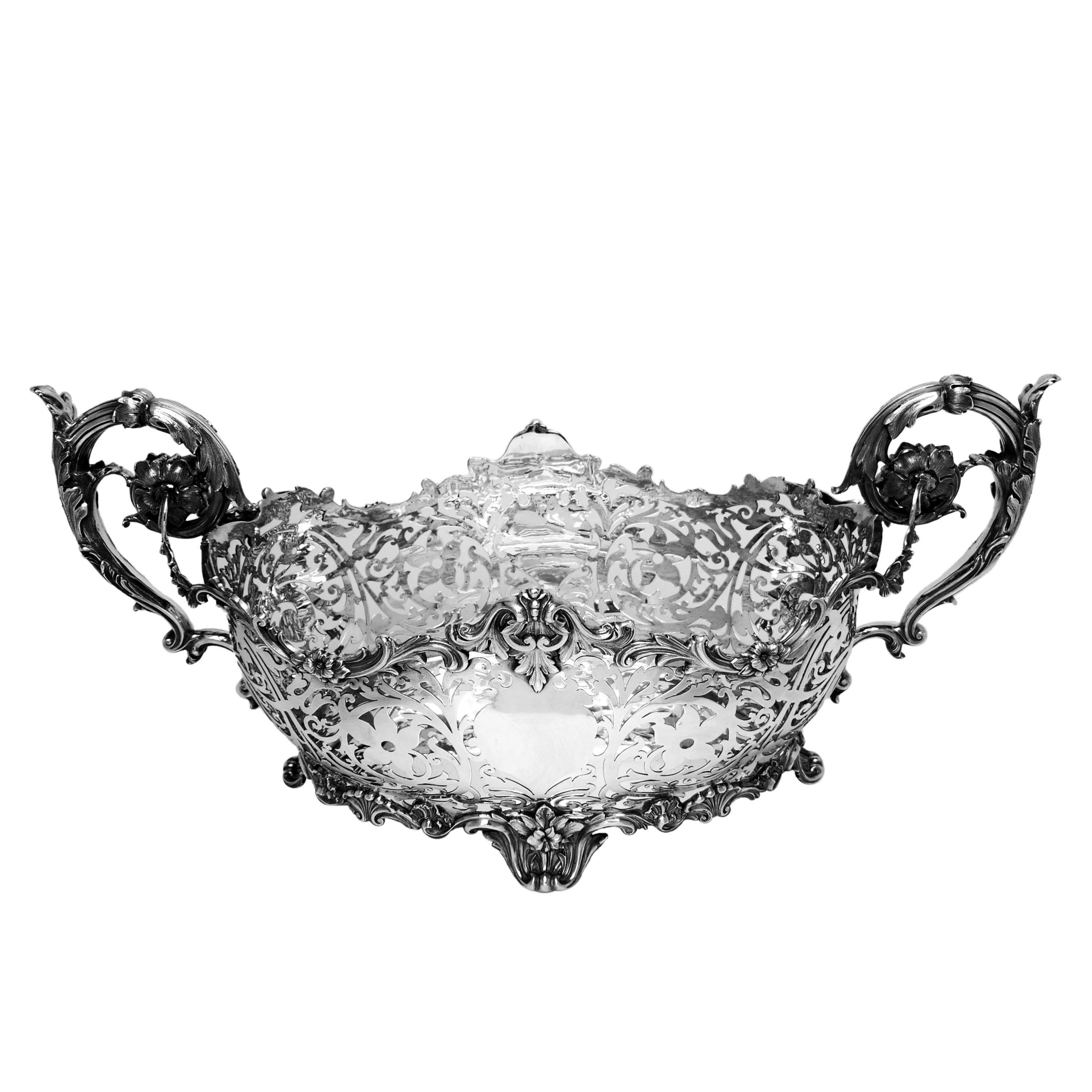 Magnífica cesta victoriana antigua de plata maciza con dos impresionantes asas florales y volutas. Esta enorme cesta de plata está decorada con un intrincado motivo floral y de volutas caladas, y tiene una cartela en blanco a cada lado. La cesta