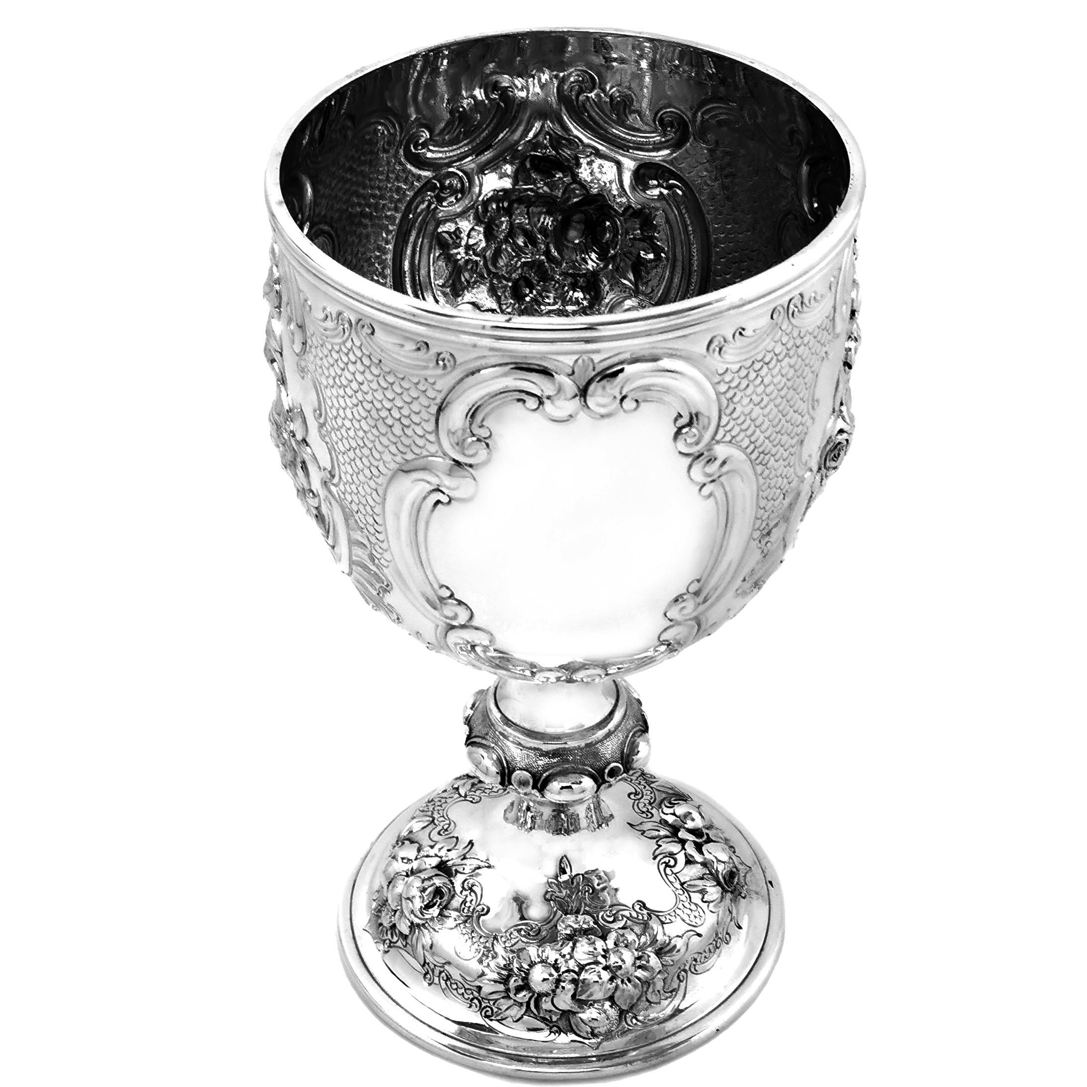 An impressive Antique Victorian solid Silver Goblet decorated with a rich variety of chased flowers. The cup features four shaped cartouches on the body, one plain and the other three featuring detailed chased floral arrangements. The foot of the