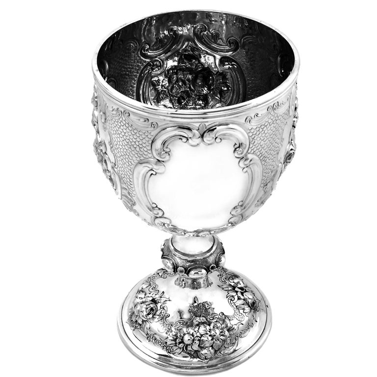 An impressive Antique Victorian solid Silver Goblet decorated with a rich variety of chased flowers. The cup features four shaped cartouches on the body, one plain and the other three featuring detailed chased floral arrangements. The foot of the