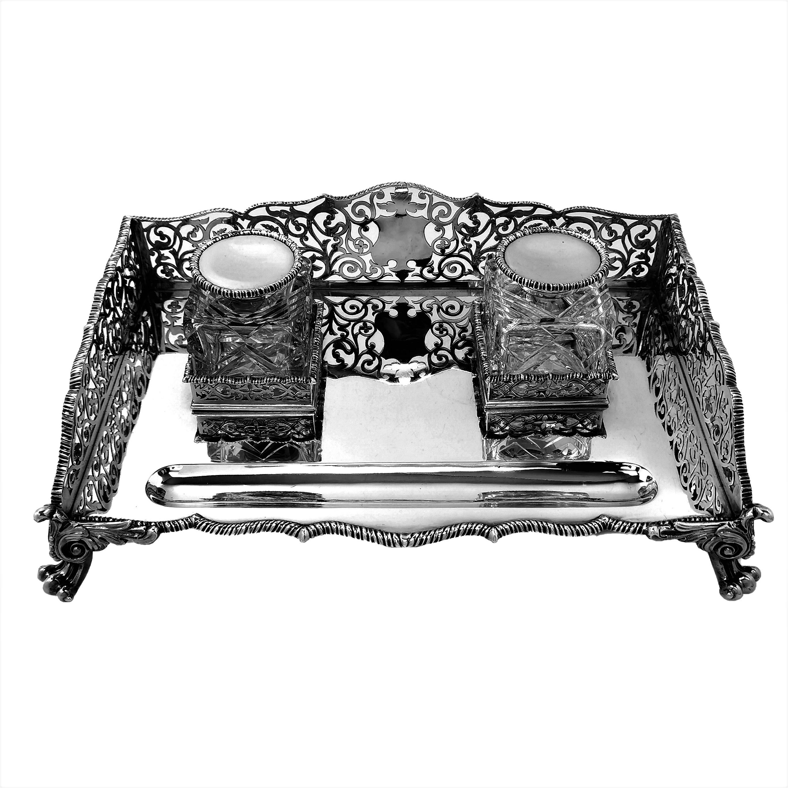 A magnificent antique Victorian solid silver ink stand with two heavy glass Inkwells with silver lids. The Inkstand has a rectangular form and stands on four impressive scroll feet. The sides of the inkwell have ornate pierced designs and a blank