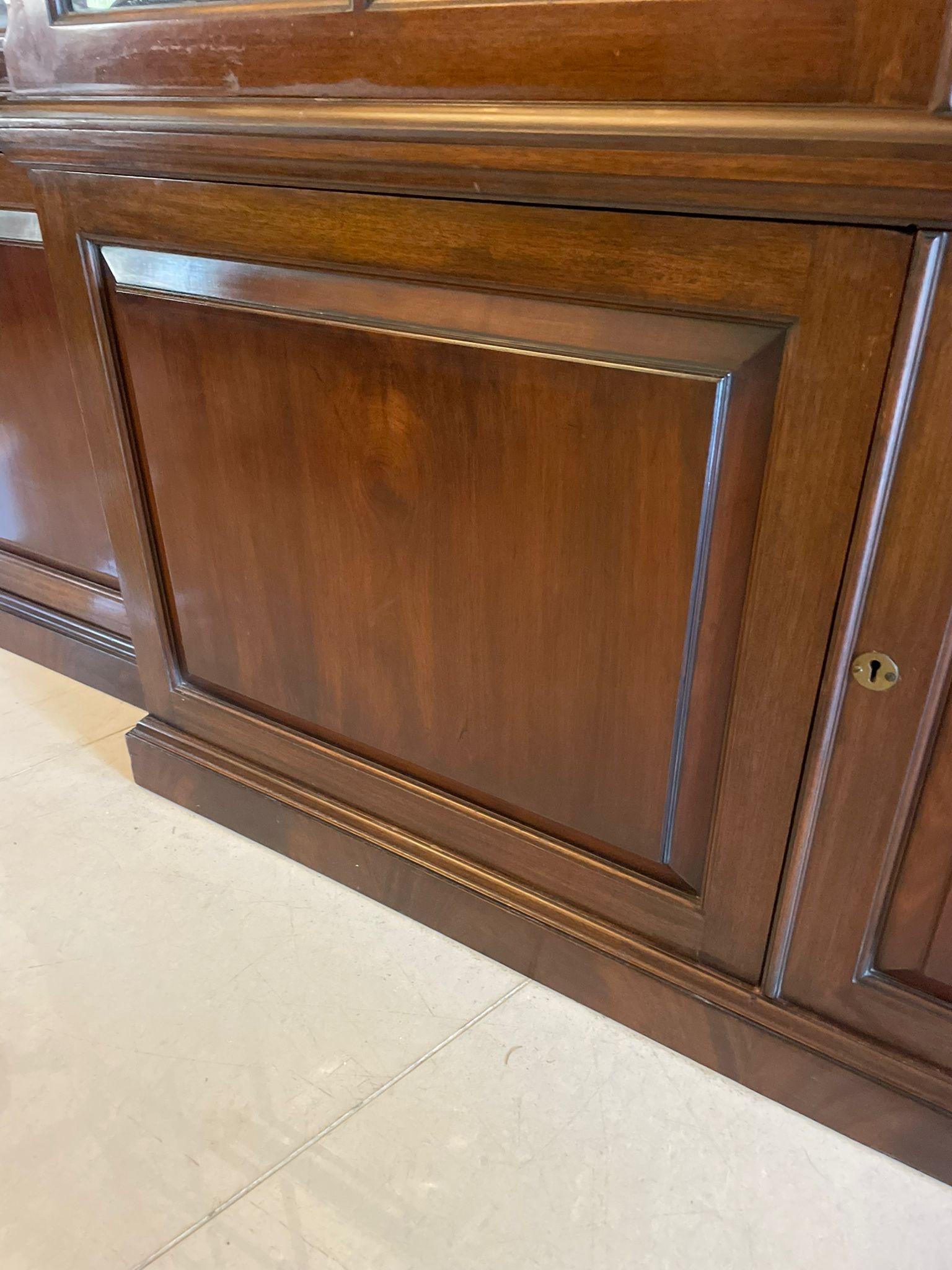 Large antique Victorian superb quality mahogany breakfront bookcase having a swan neck moulded pediment above a superb quality figured mahogany cornice above four astral glazed doors opening to reveal twelve adjustable shelves above four figured