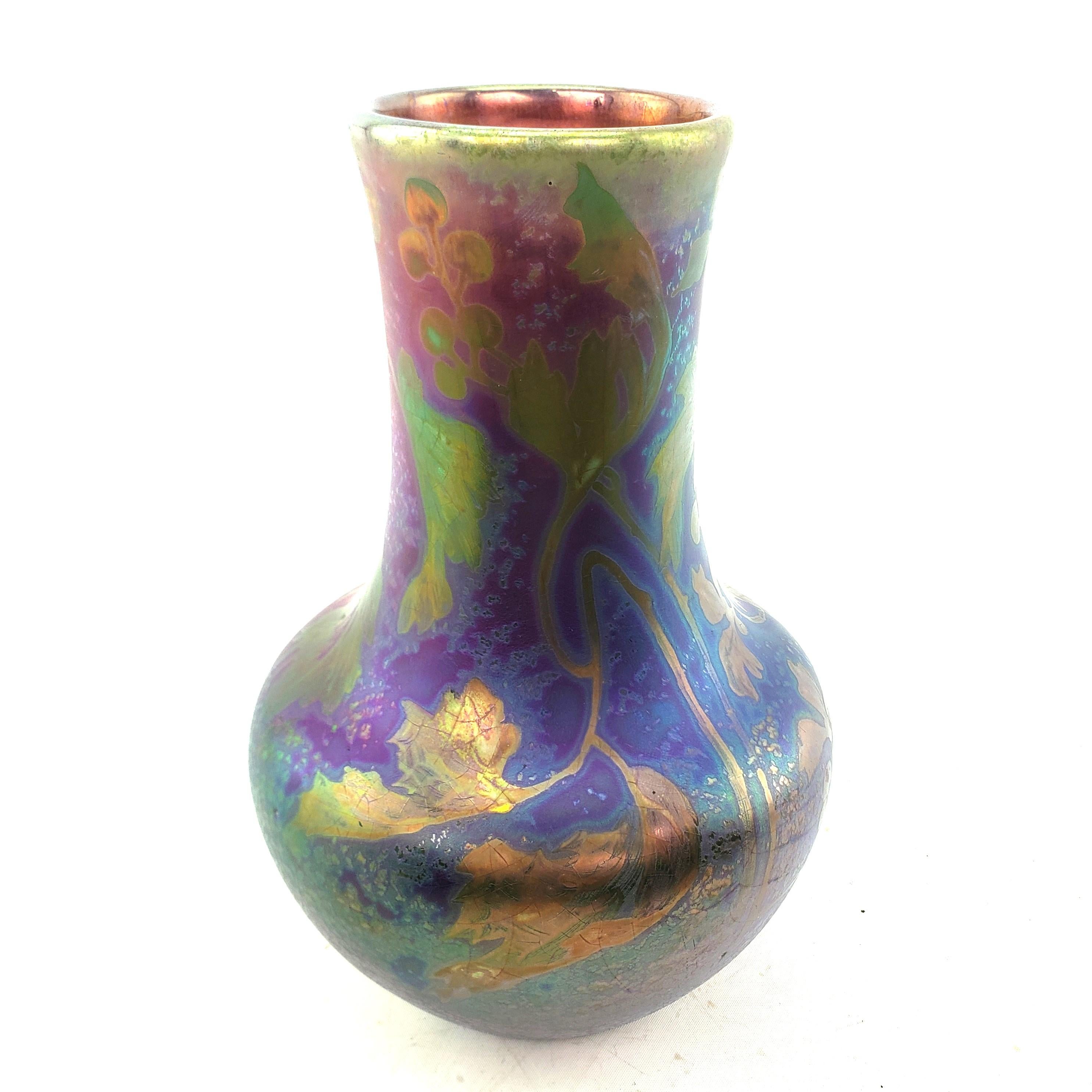 This vase was made by the renowned Weller Pottery factory of the United States in approximately 1910 in the period Art Nouveau style. The vase is done with a high irridescent cobalt blue, green and purple with stylized floral decoration with a gloss