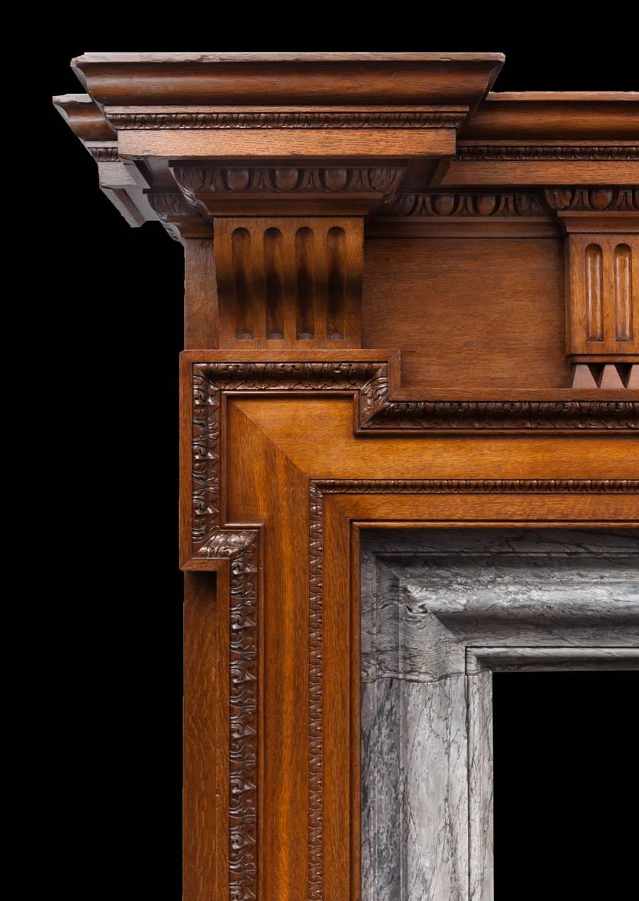 A very large antique carved oak and grey Bardiglio marble mantelpiece.

This is an extremely well carved English Palladian style oak fireplace of great proportions. The fireplace features a centre frieze with swags of acorns, dog-leg cornered