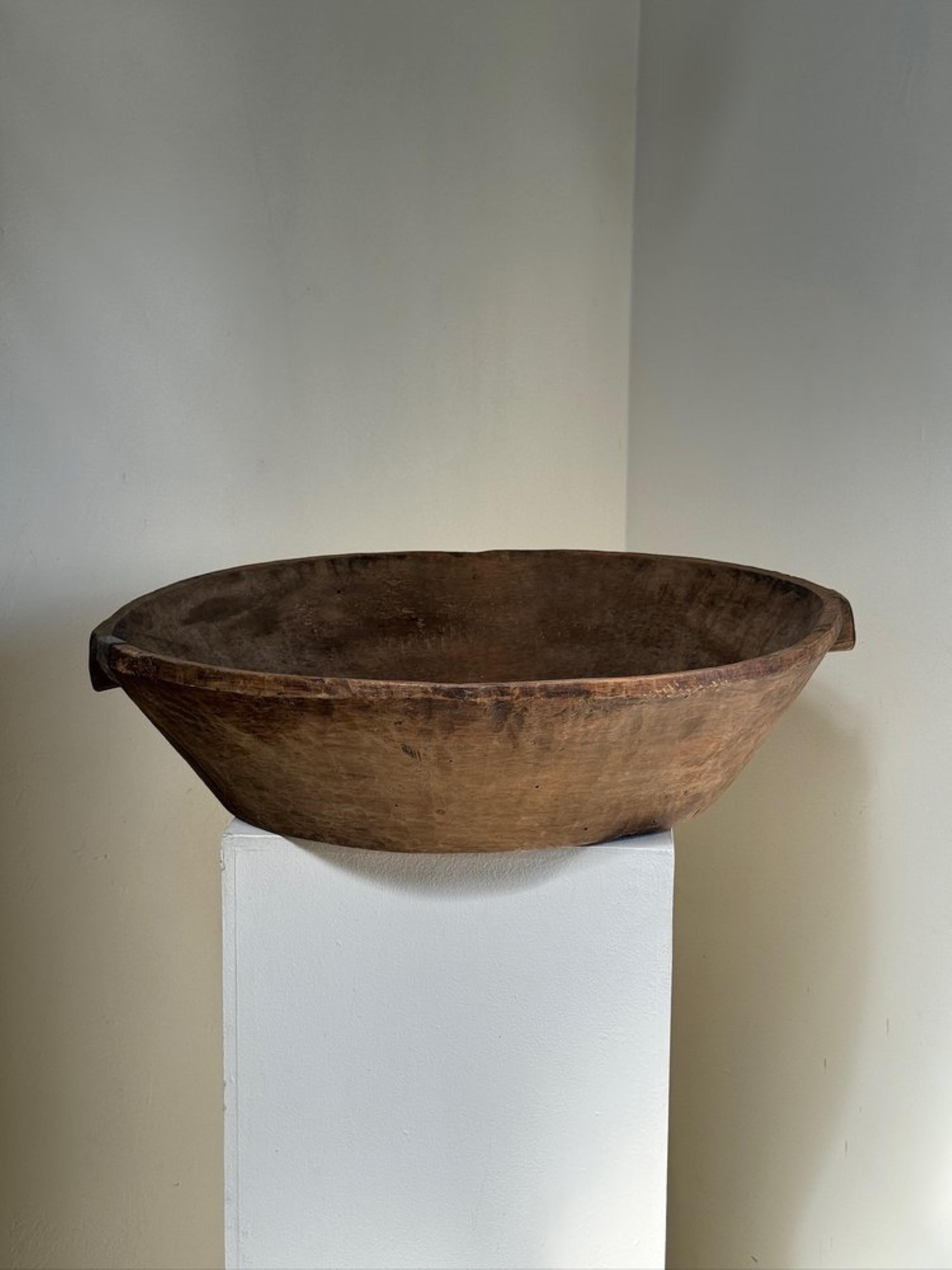 This sizable vintage wooden bowl embodies the essence of wabi-sabi, showcasing a primitive charm in its solid wood construction. Bearing the marks of its age and history, it remains in excellent vintage condition. Its distinct character adds