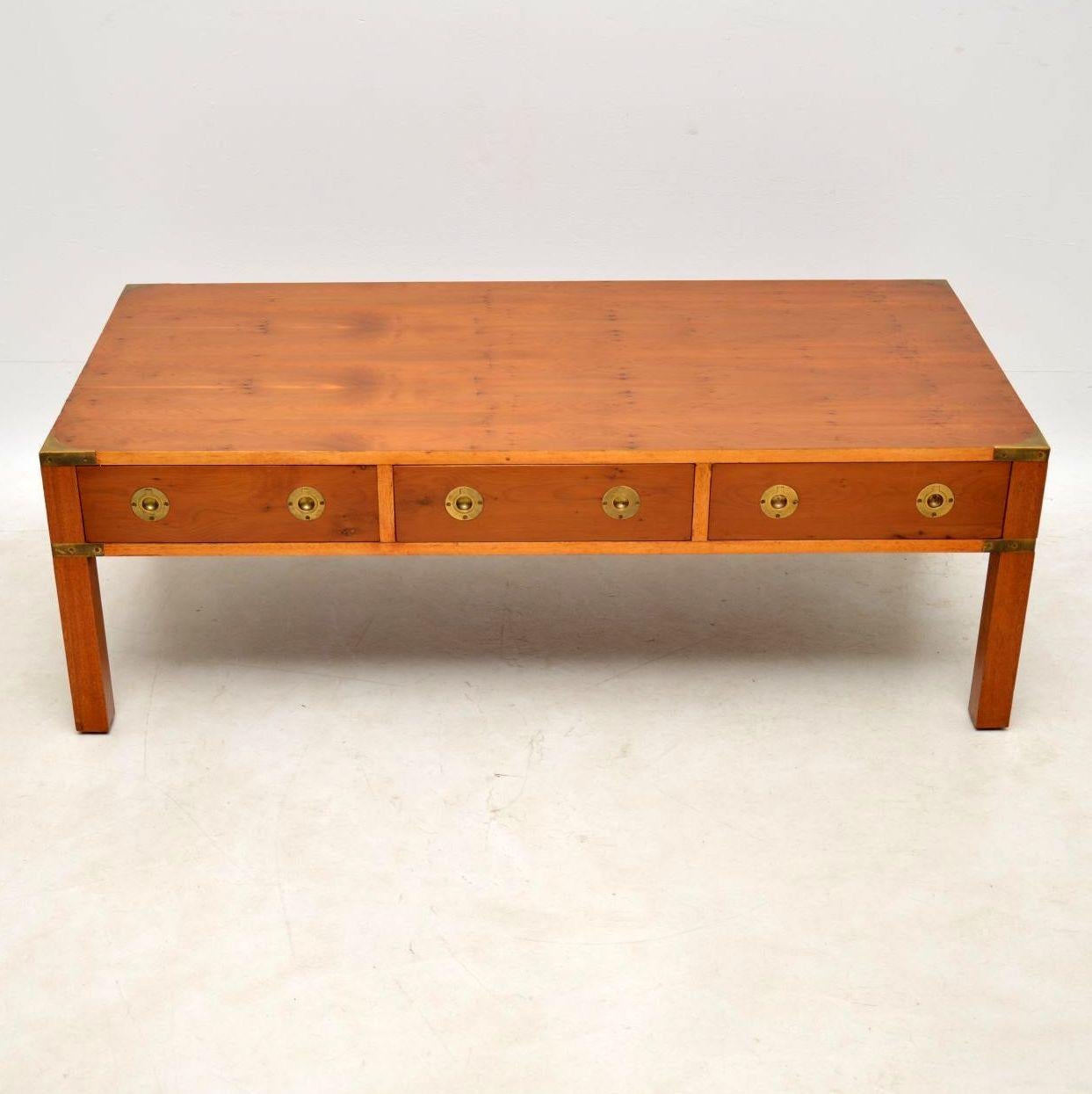 Large antique campaign style coffee table in yew wood with three drawers on one side and dummy drawers on the other side. The drawers have military style inset brass handles and there are brass fittings on the corners too. This coffee table is of