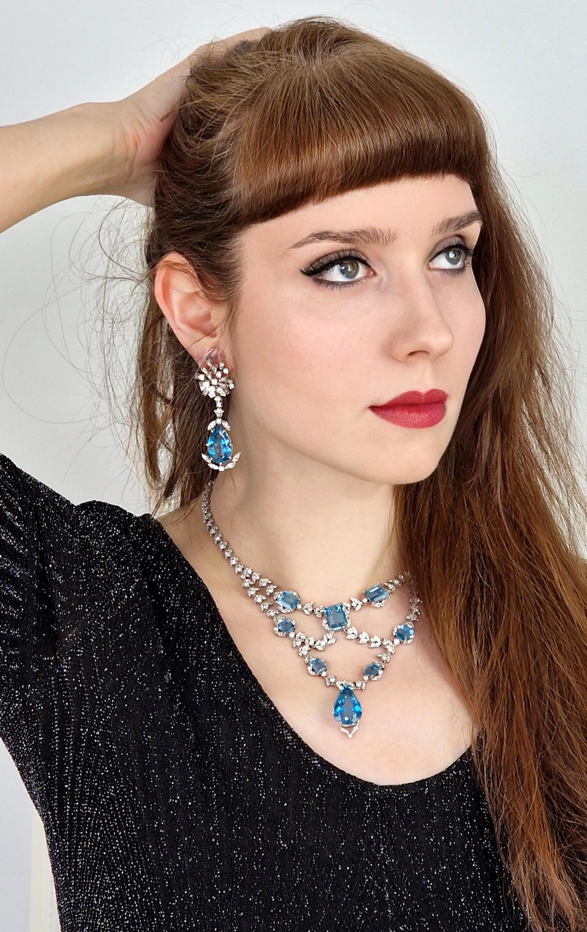 A classic and absolutely stunning piece, this is a one-of-a-kind necklace and earrings suite featuring immaculately matched dark blue emerald cut aquamarines mounted on delicate swallow wing motifs set with fine white brilliant diamonds. 