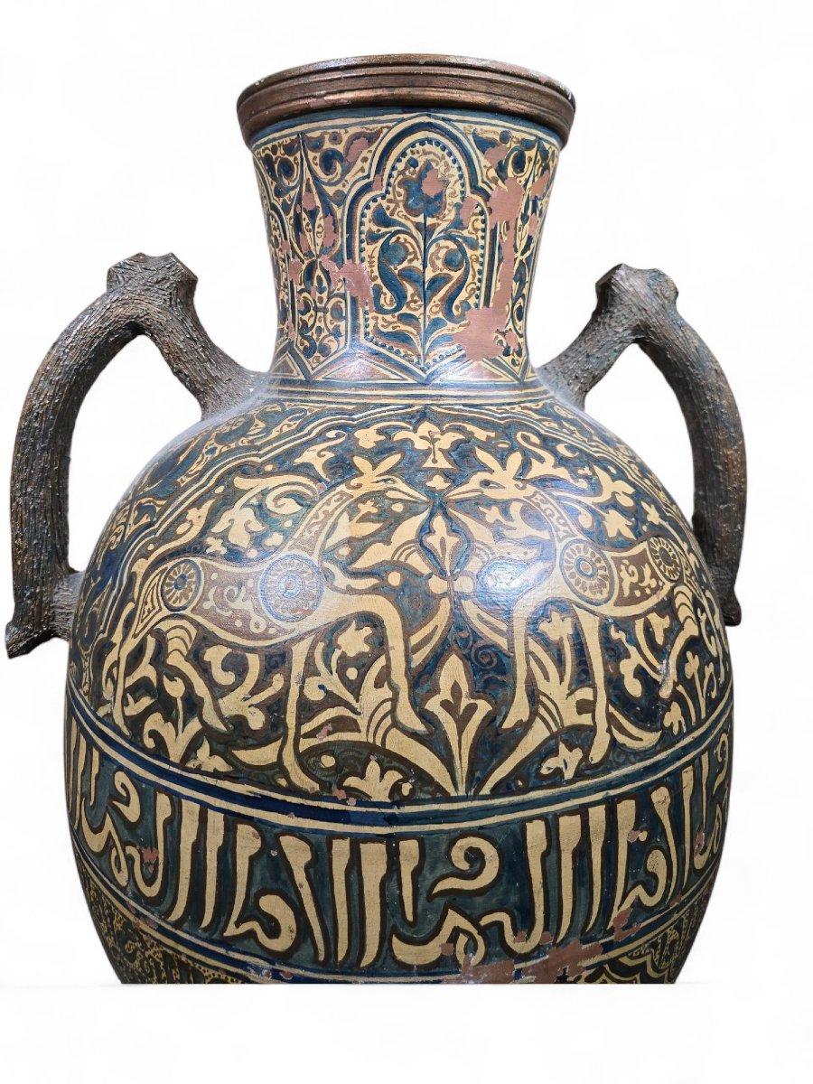 Impresionante jarrón árabe del siglo XIX, de terracota vidriada, claramente inspirado en Andalucía, que evoca los refinados motivos decorativos del palacio de la Alhambra de Granada durante el periodo de Al-Andalus.

Este jarrón se distingue por su