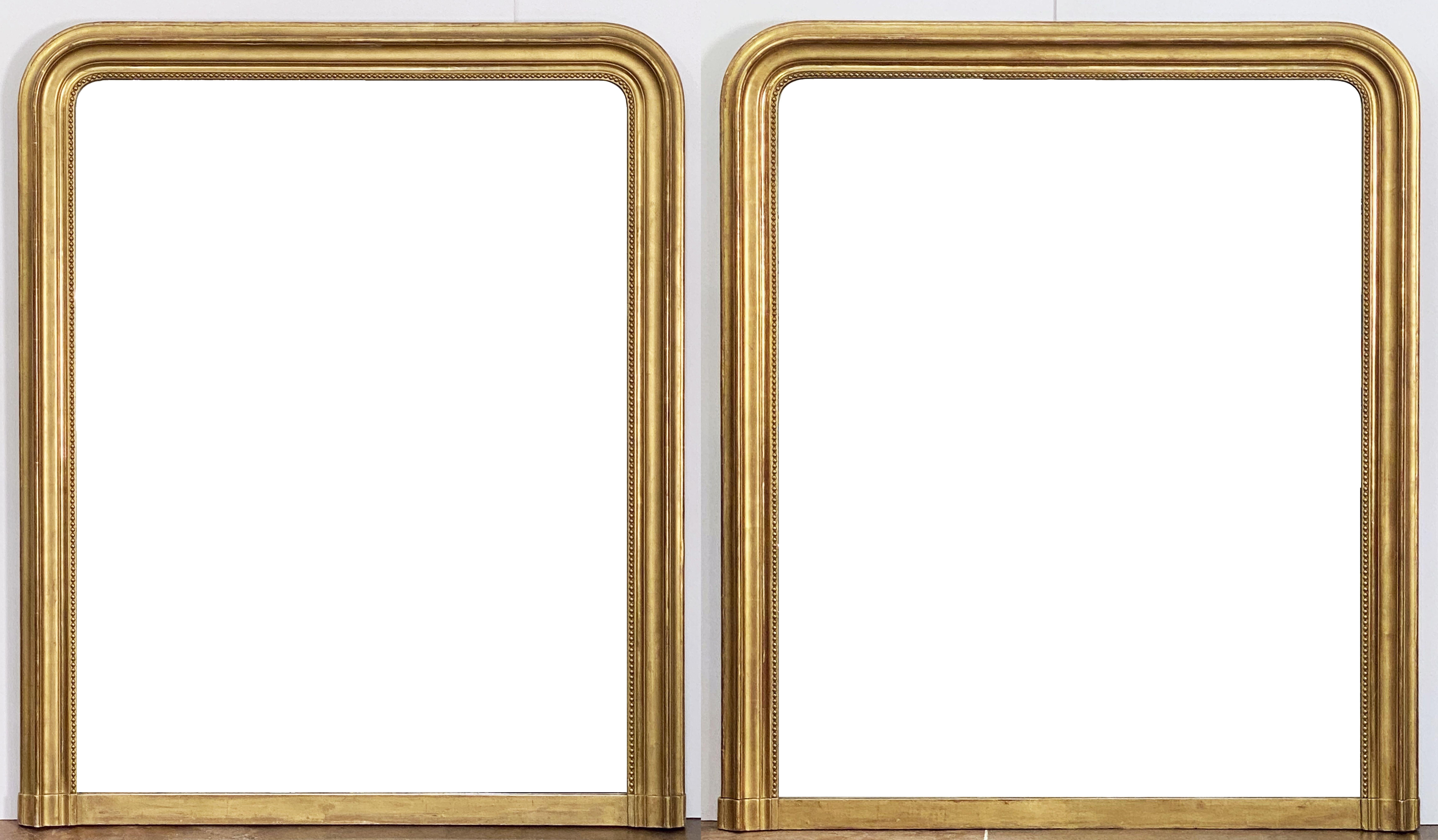 A fine large Louis Philippe gilt wall mirror featuring a lovely moulded surround of patinated gold leaf with a beaded trim around the inside frame.

Dimensions: H 52 inches x W 43 1/2 inches

There are two mirrors of this design and general size