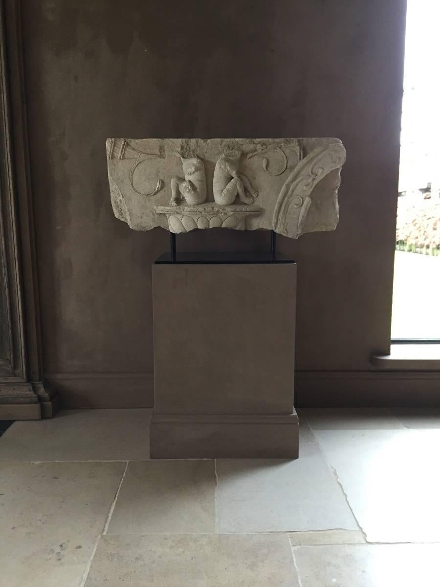 Large early 17th century French architectural fragment in sandstone. This piece features two putti blowing a Horn sitting on a lobbed pedestal and flanked on the right hand side with a moulded arch fragment. Originally this piece would have been
