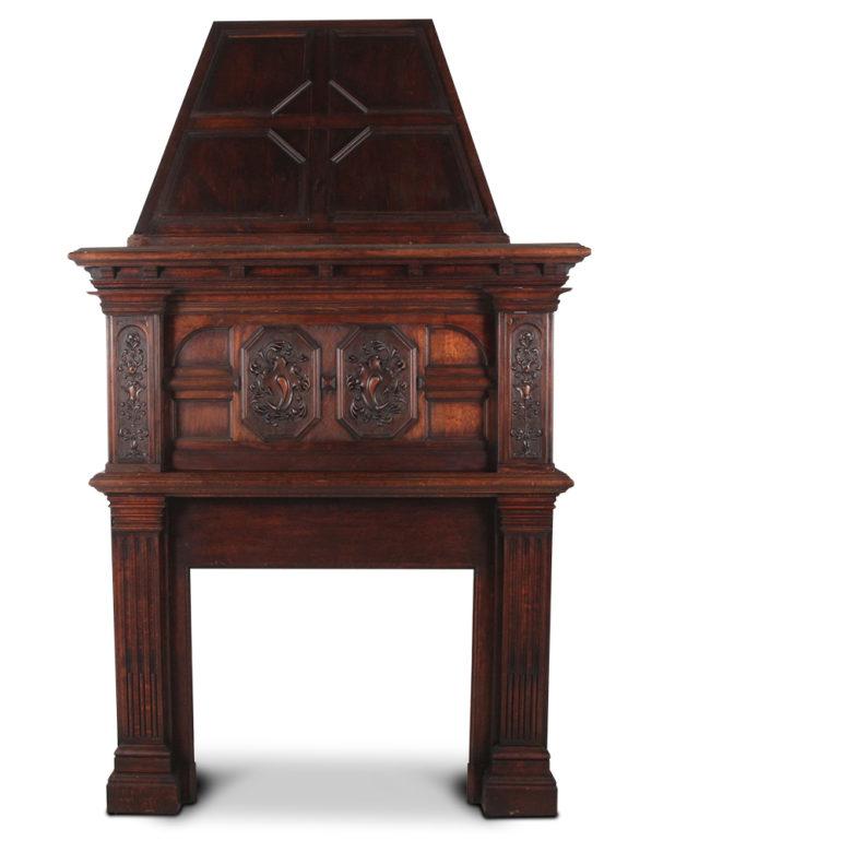 An impressive, solid oak French mantle, the lower paneled fire surround with fluted pilasters and surmounted by a paneled upper case with carved inset walnut details, the whole further capped by a paneled oak chimney piece, circa 1900.

Measures: