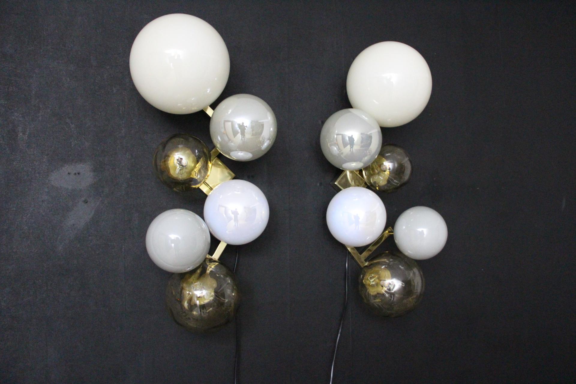 This magnificent pair of sconces is a real wall decor. It is made of a brass frame on which 6 handmade Murano glass of various sizes and colors are set.
Globes are milky white,iridescent grey,gold and iridescent aniseed color.
It looks like a