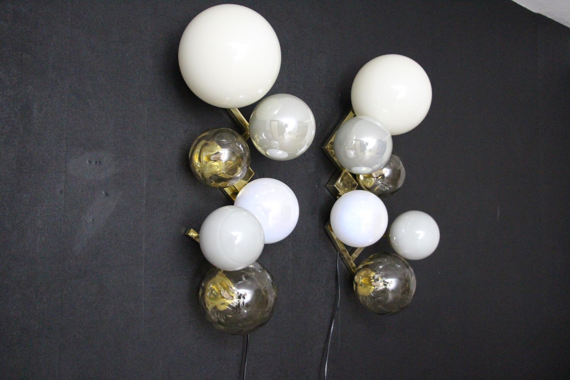 This magnificent pair of sconces is a real wall decor. It is made of a brass frame on which 6 handmade Murano glass of various sizes and colors are set.
Globes are milky white,iridescent grey,gold and iridescent aniseed color.
It looks like a