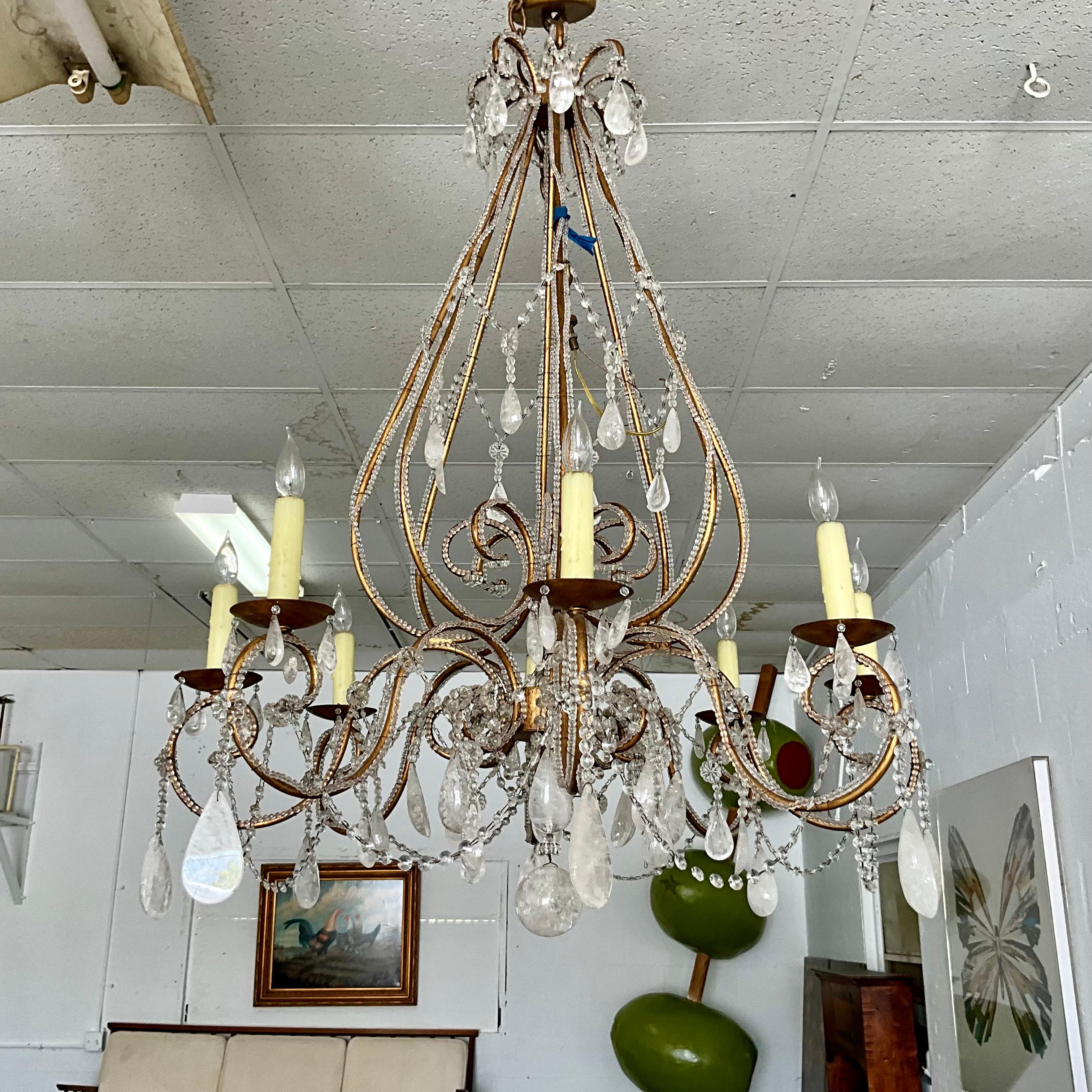 Stunning 1960’s rock crystal gilt metal chandelier with eight scrolled arms encompassed in glass faceted beading with rock crystal prisms, and a large 3” sold rock crystal sphere hanging from the bottom center of the chandelier.  The chandelier