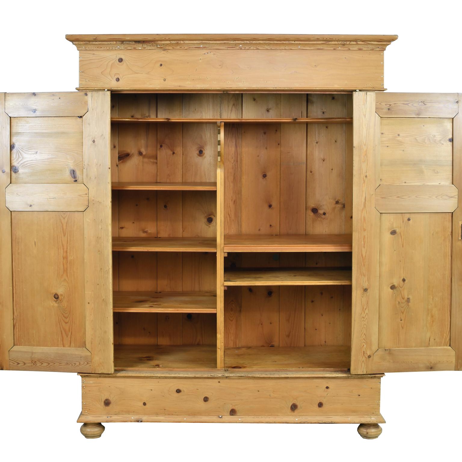 A large armoire in a light honey-colored pine with two paneled doors, leather key plates and turned bun feet. North German, circa 1830. Doors open flush with the front of the piece, allowing easy access to the interior. Comes with key and working